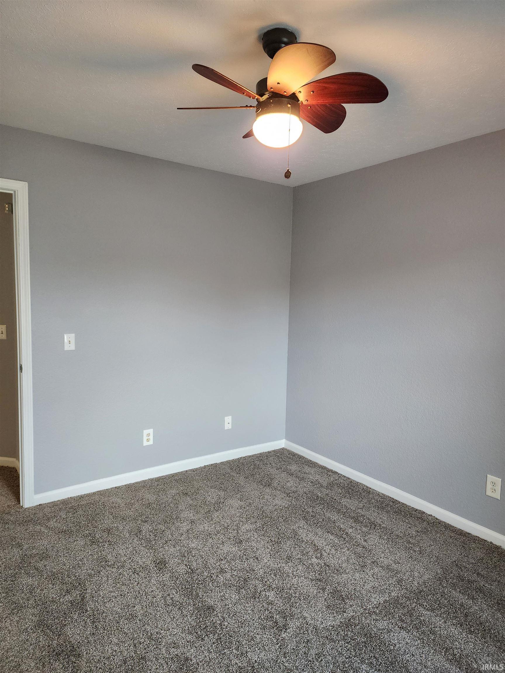 Empty room with dark carpet and ceiling fan