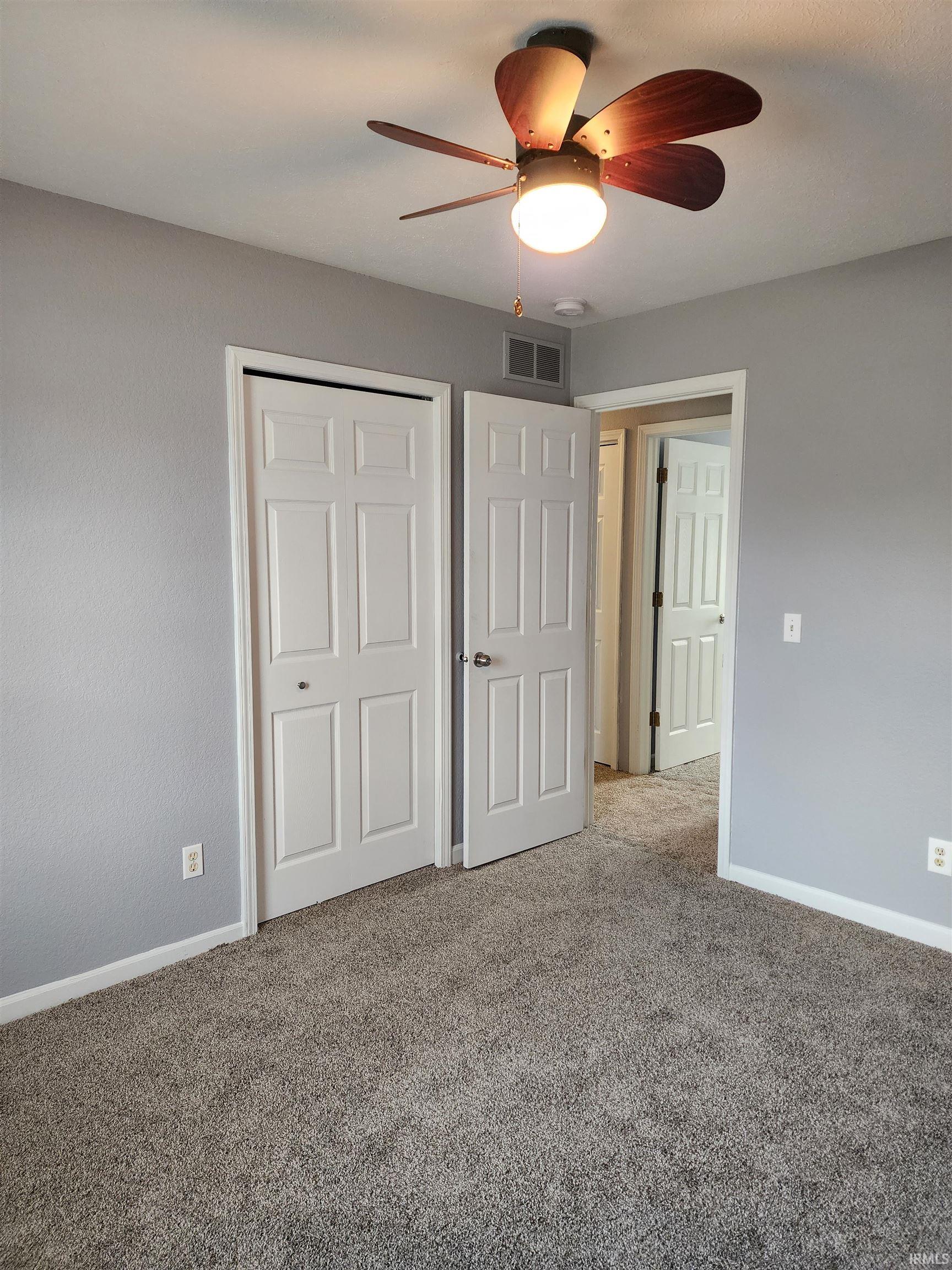 Unfurnished bedroom with a closet, ceiling fan, and carpet floors