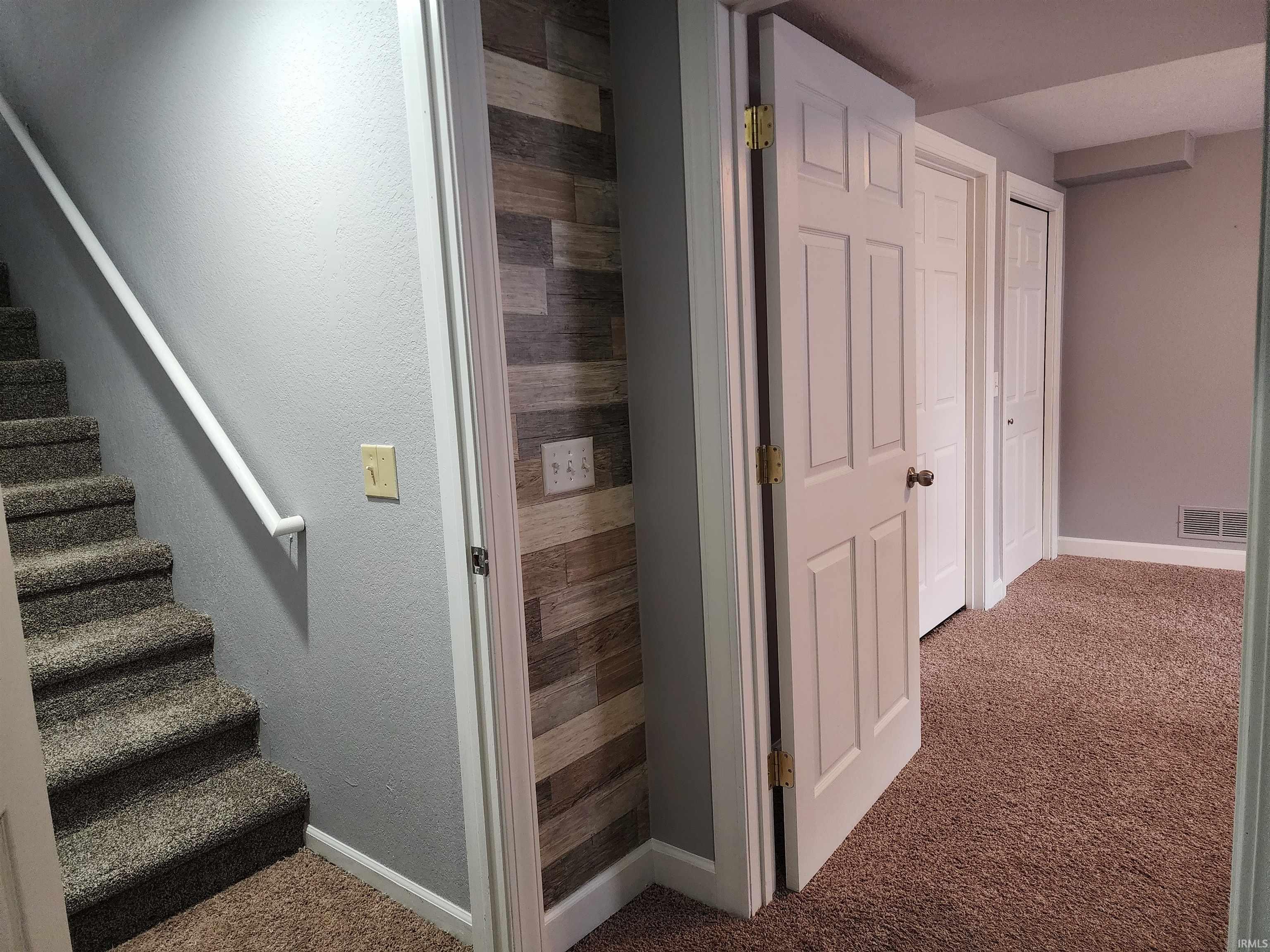 Staircase with carpet flooring and a textured wall