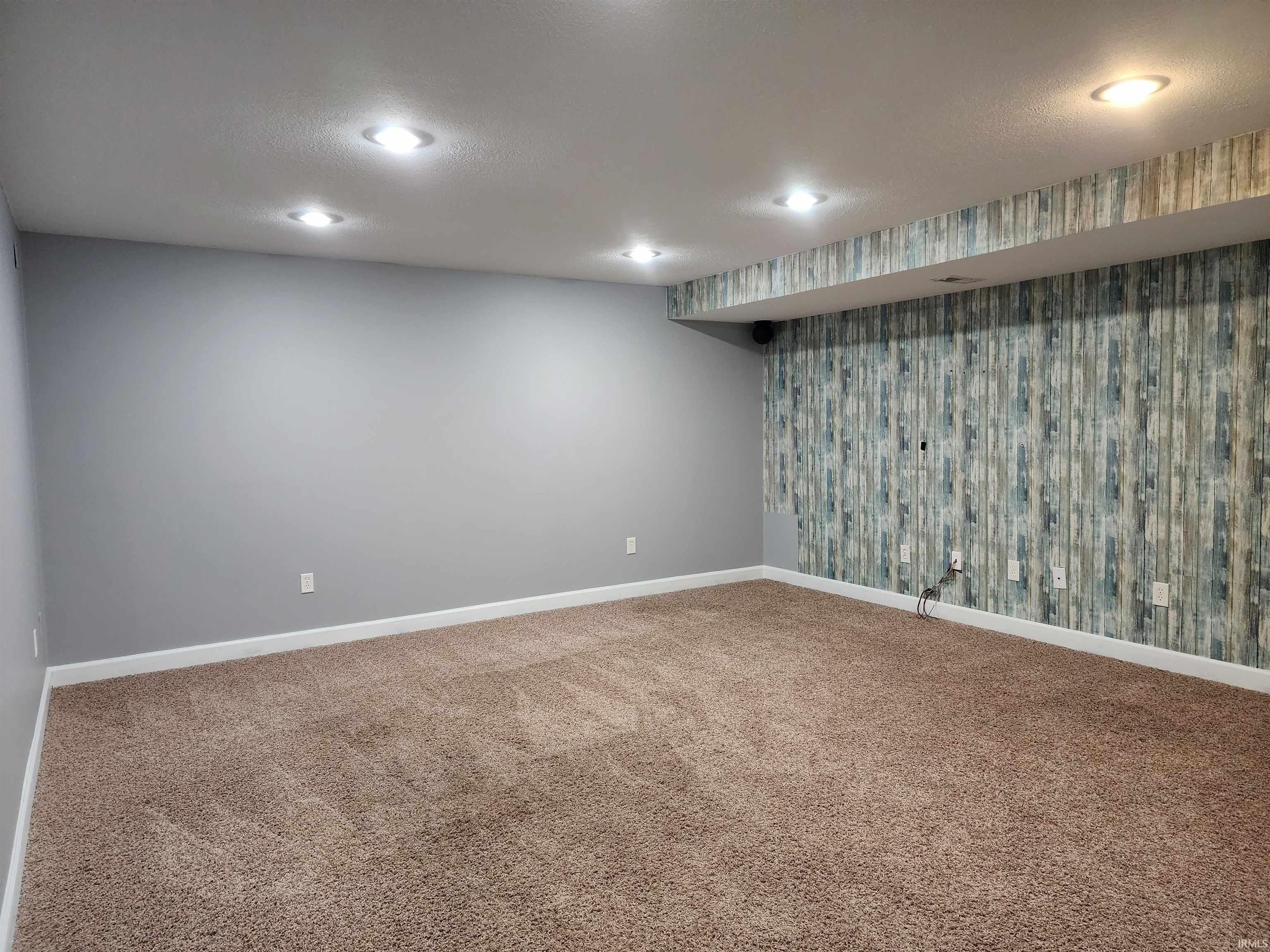 Finished basement with wallpapered walls, carpet, recessed lighting, and an accent wall