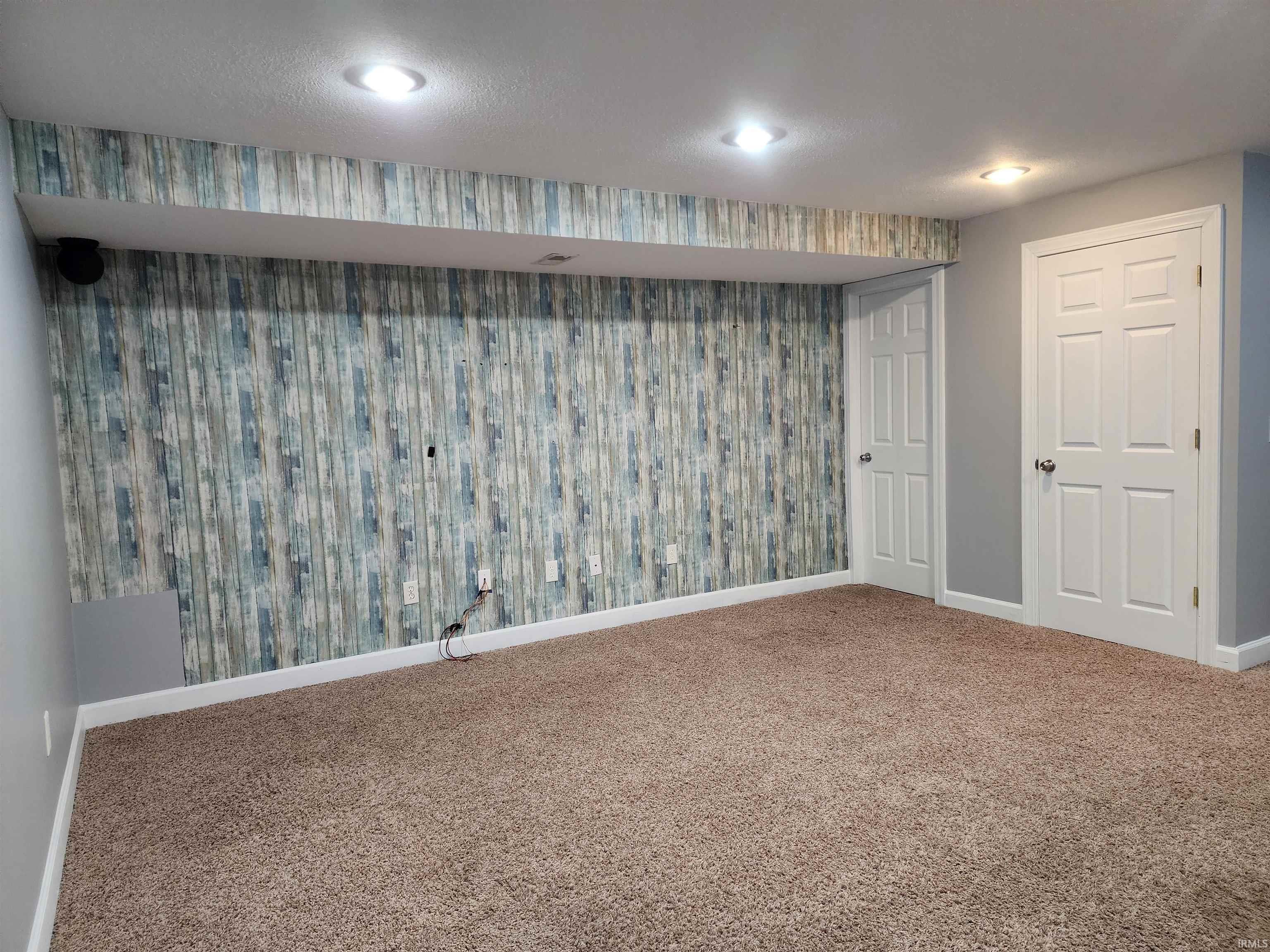 Finished below grade area featuring carpet, wallpapered walls, and an accent wall