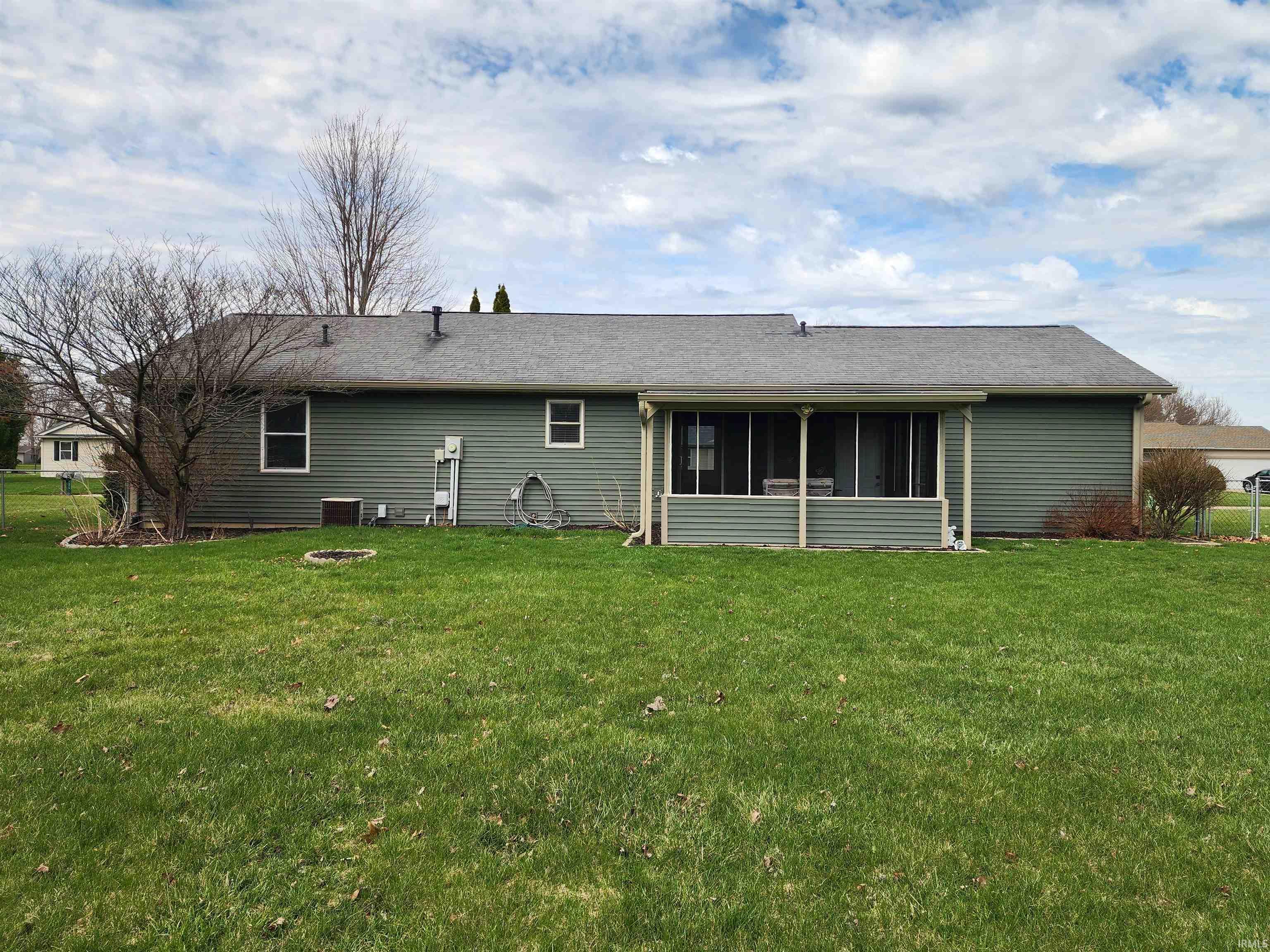Rear view of house featuring a sunroom, a yard, roof with shingles, and an outdoor fire pit