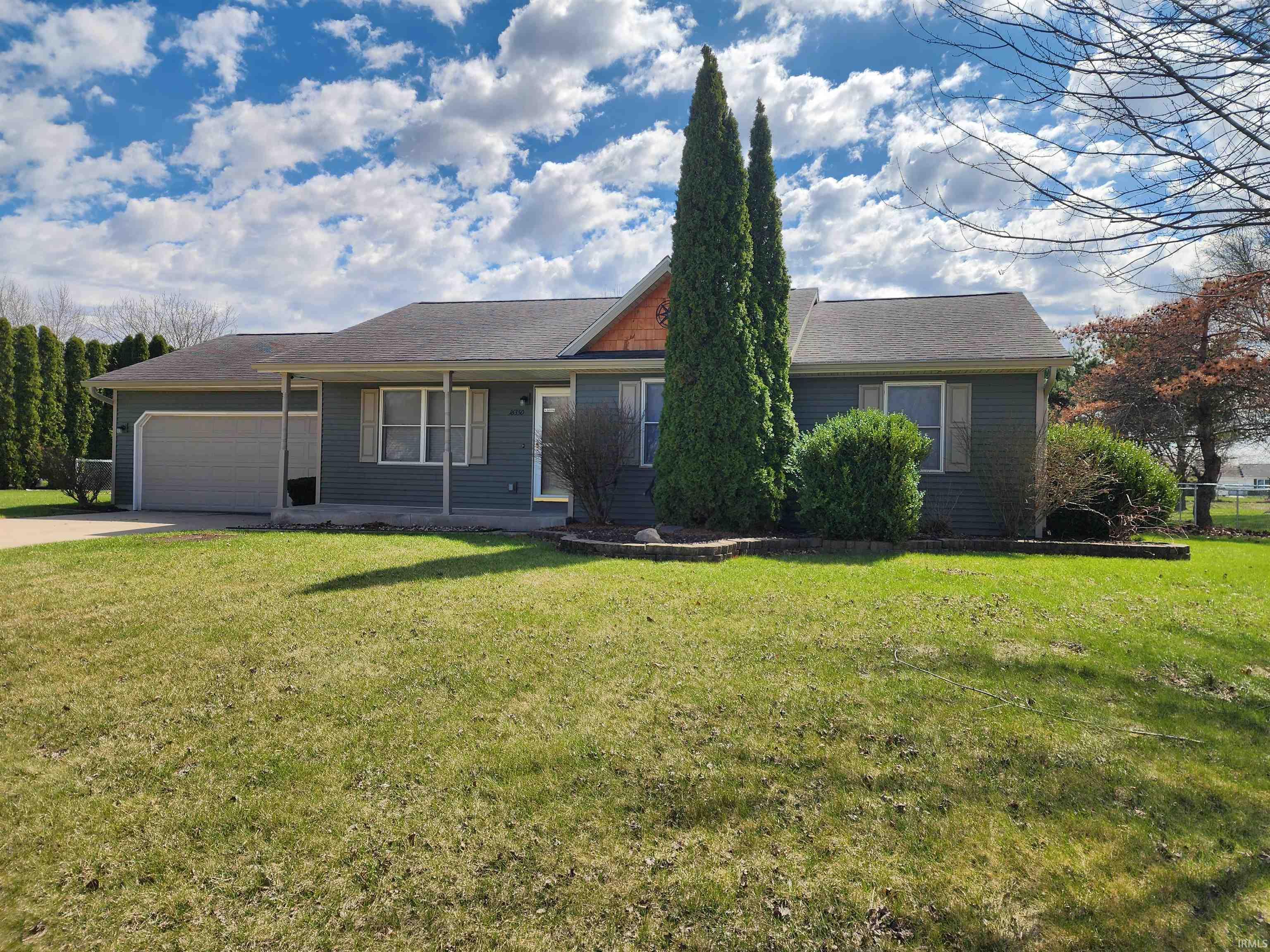 Ranch-style house featuring a front lawn, an attached garage, and driveway