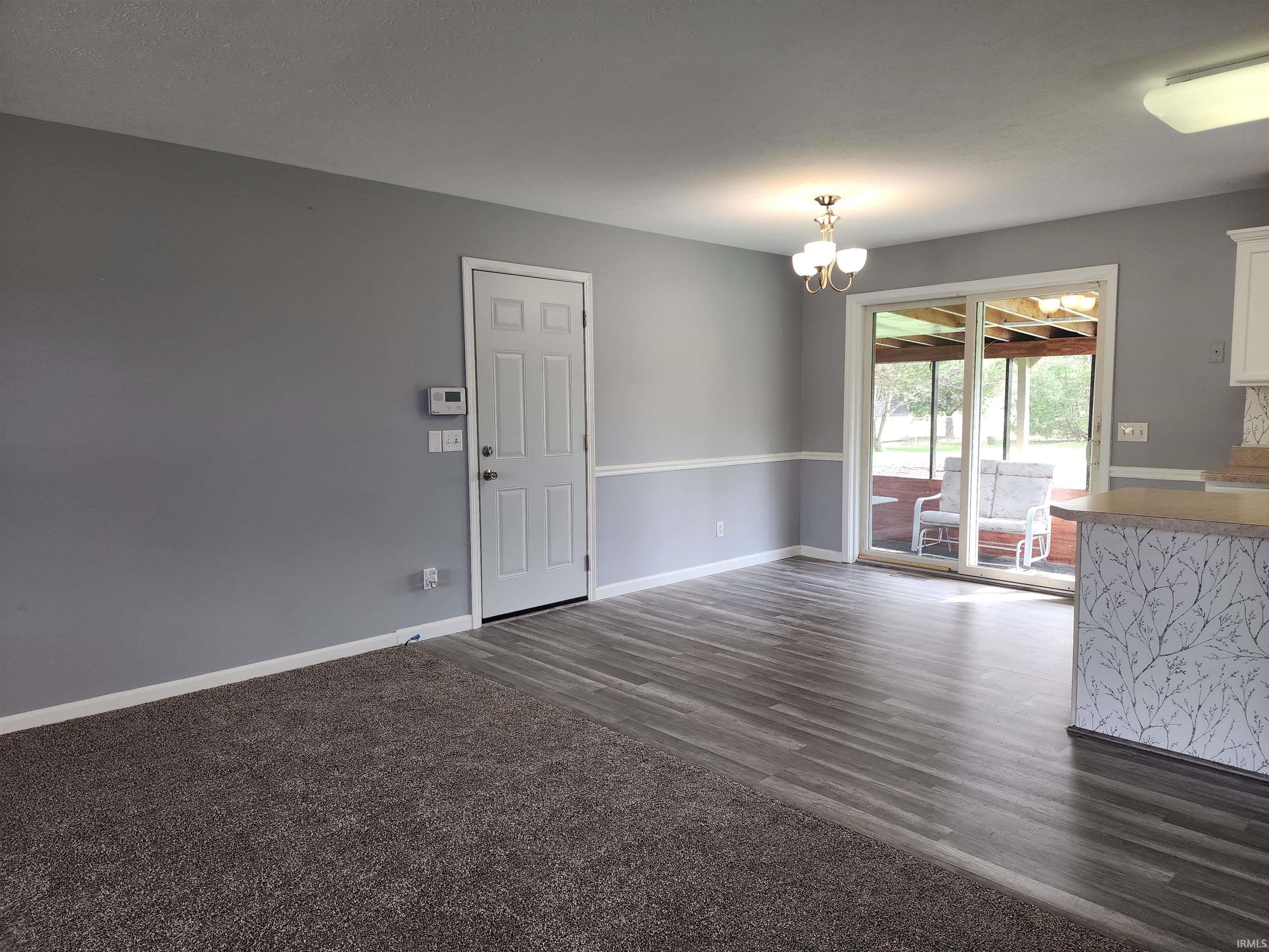 Unfurnished dining area featuring suspended lighting and dark wood finished floors