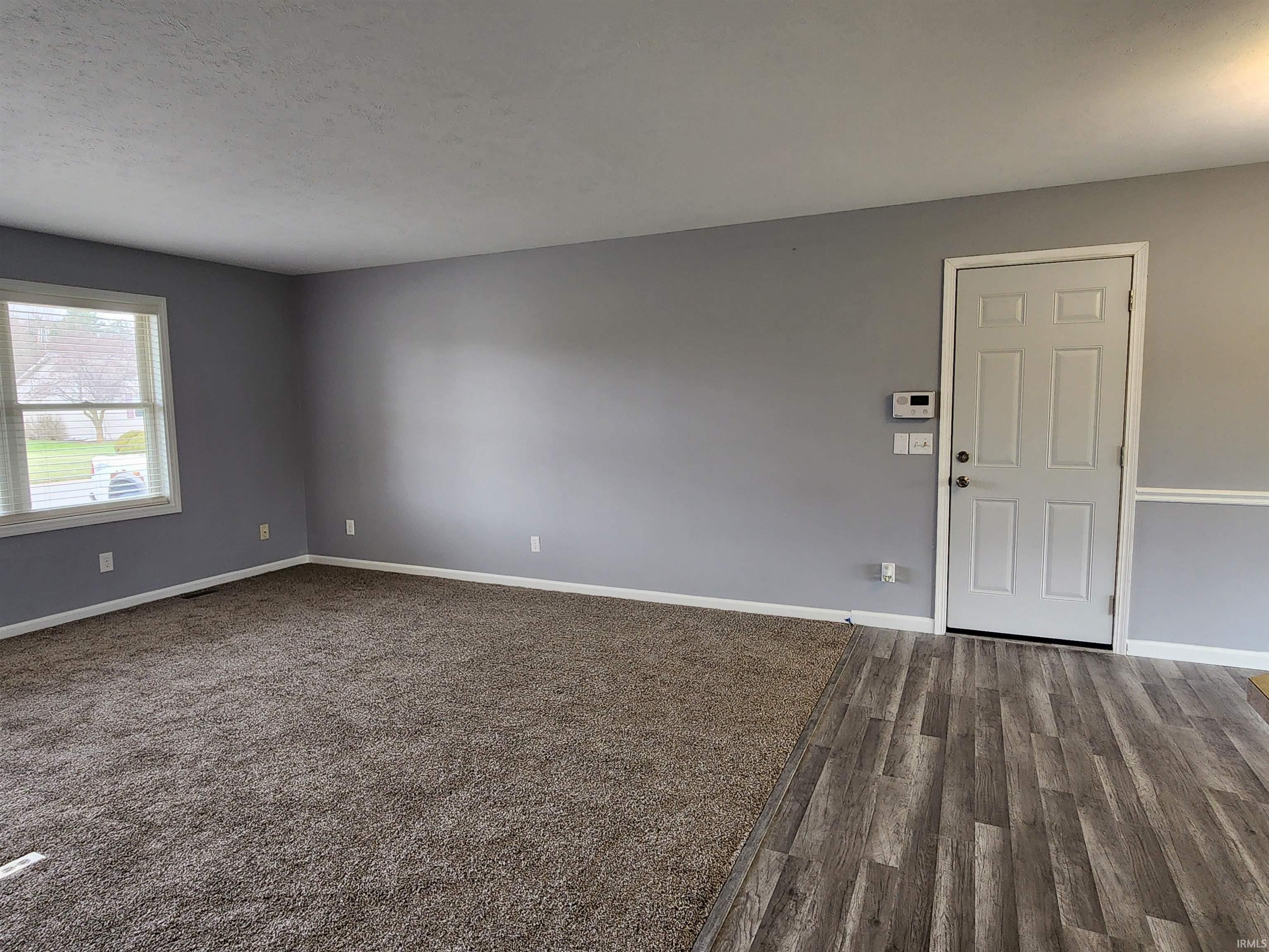 Unfurnished room featuring dark wood-style flooring and a textured ceiling