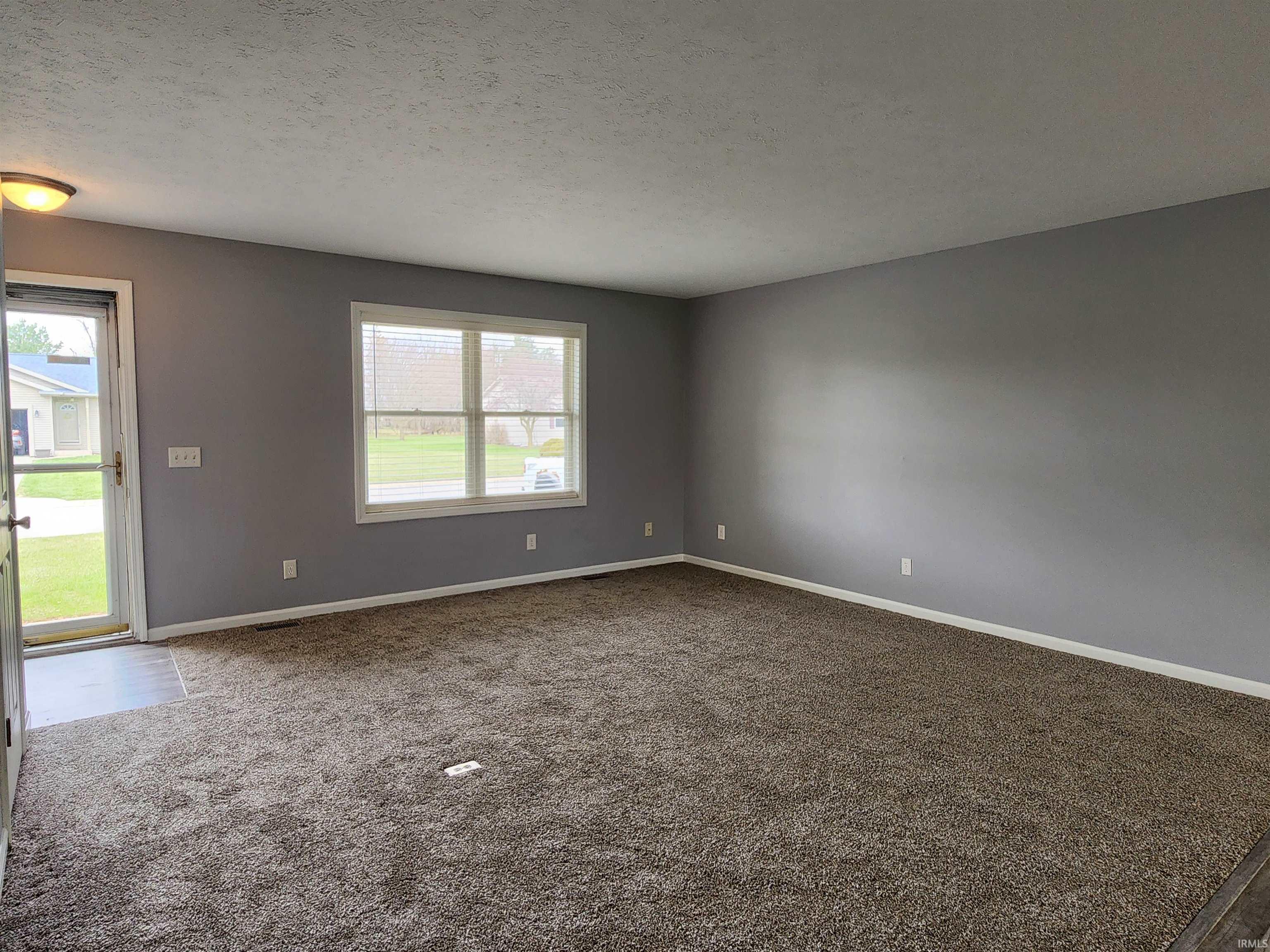 Unfurnished room with a textured ceiling and dark carpet