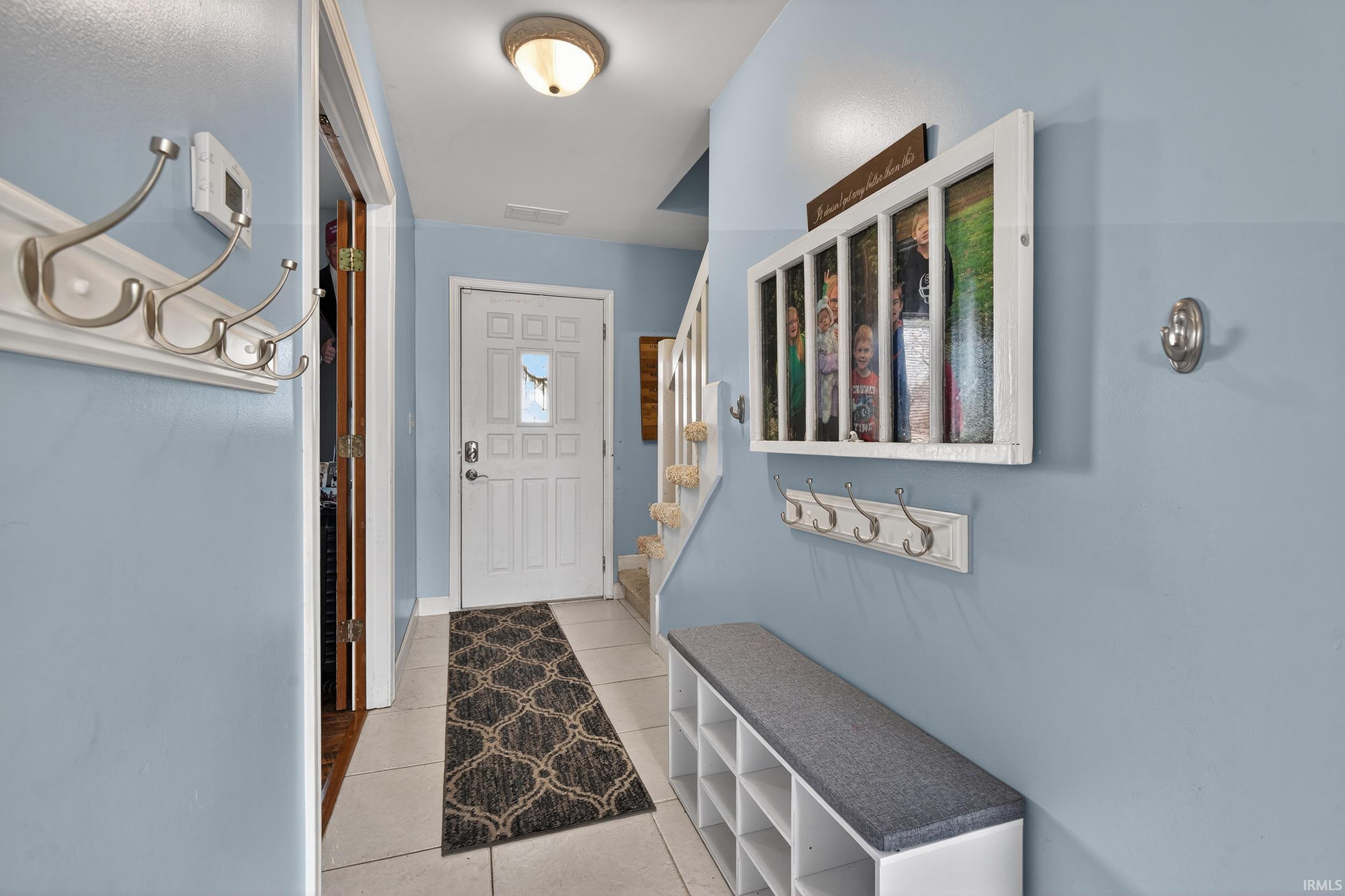 Doorway with tile patterned flooring and stairway
