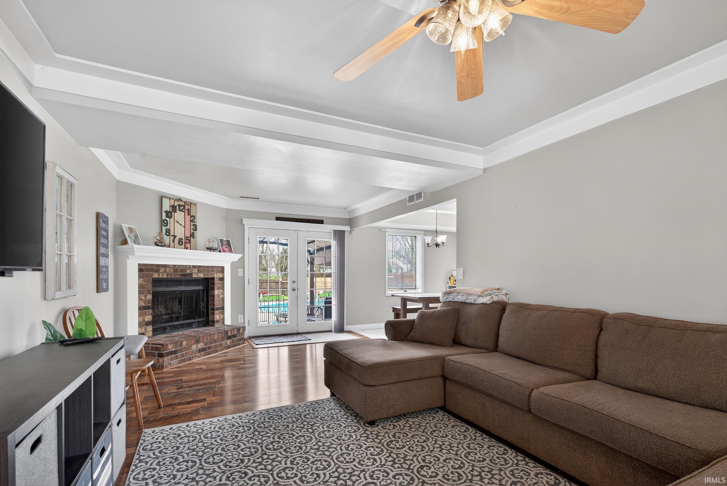 Living room with french doors, a fireplace, ceiling fan, dark wood finished floors, and suspended lighting