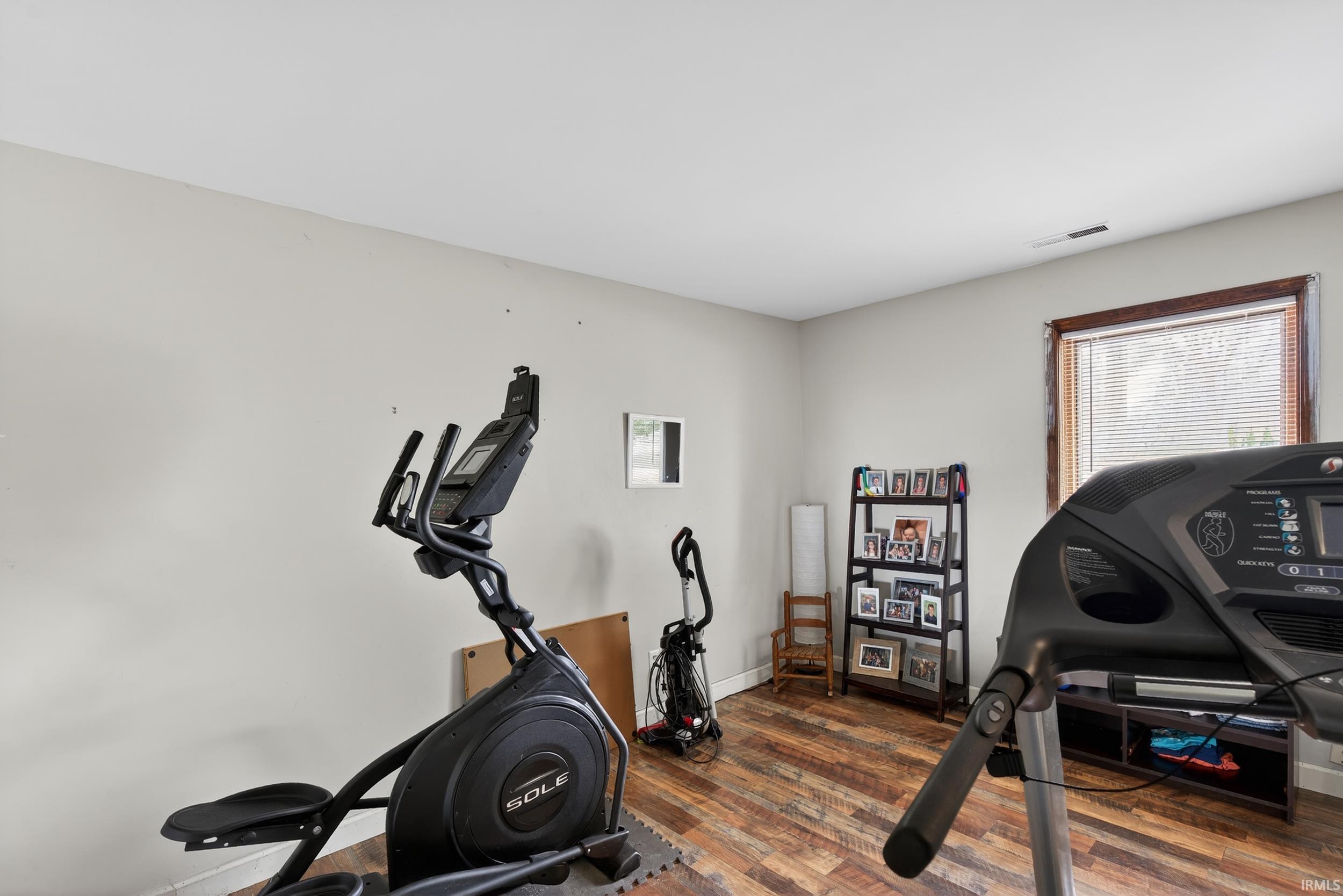 Workout area featuring dark wood-style floors and baseboards