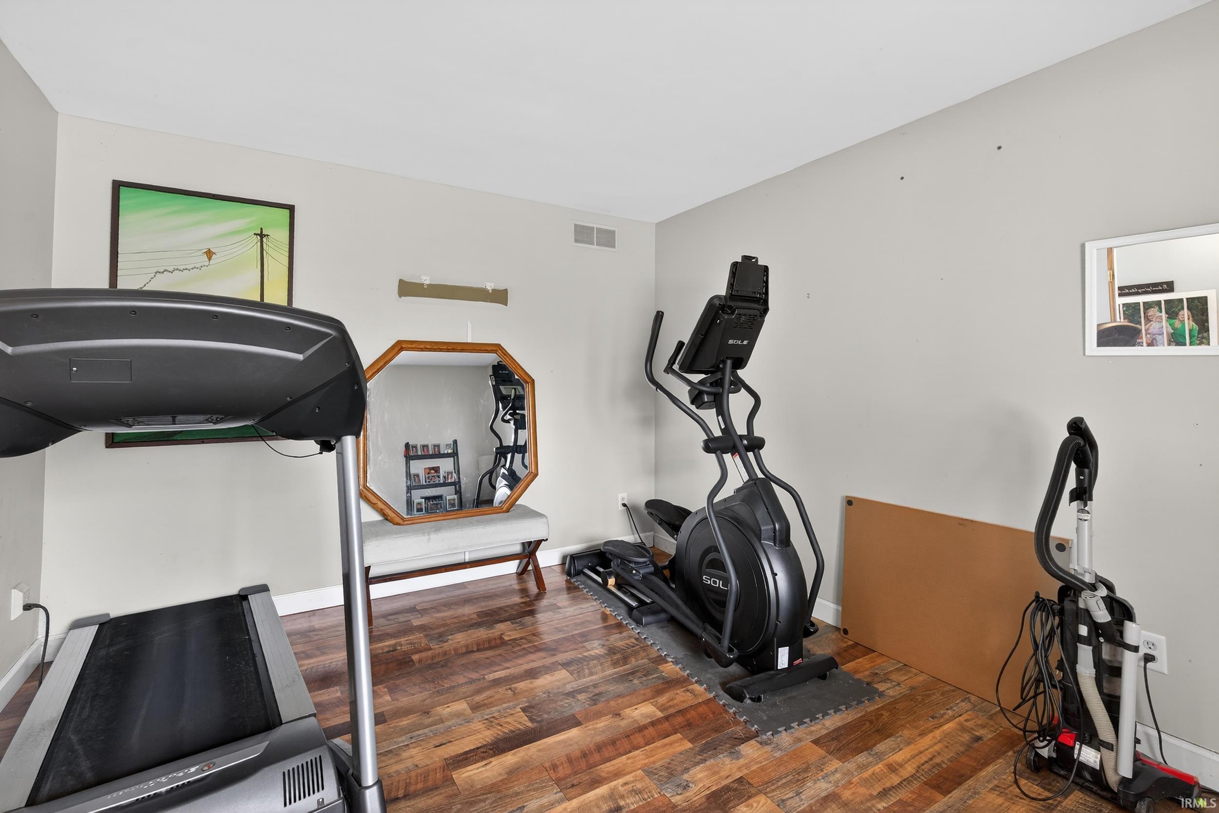 Exercise room featuring dark wood finished floors and baseboards