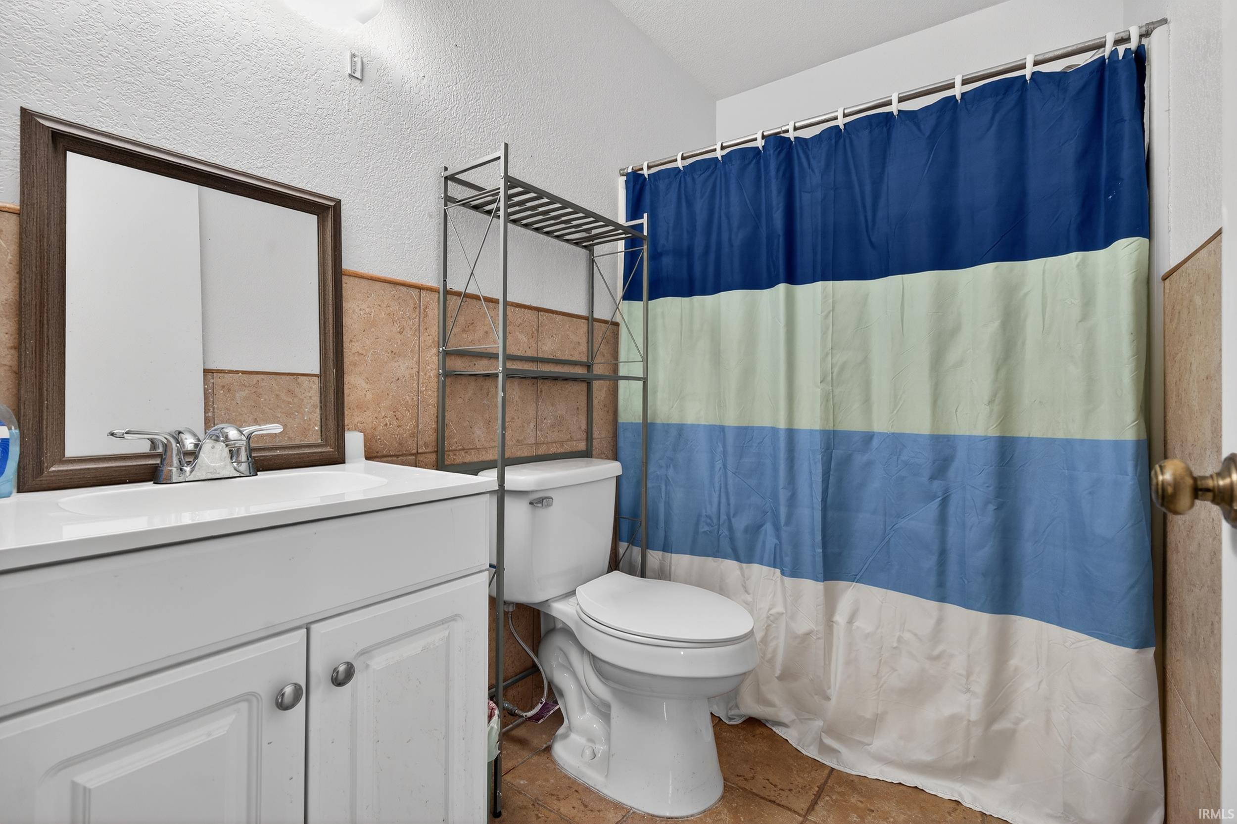 Bathroom featuring vanity, a shower with curtain, and a textured wall