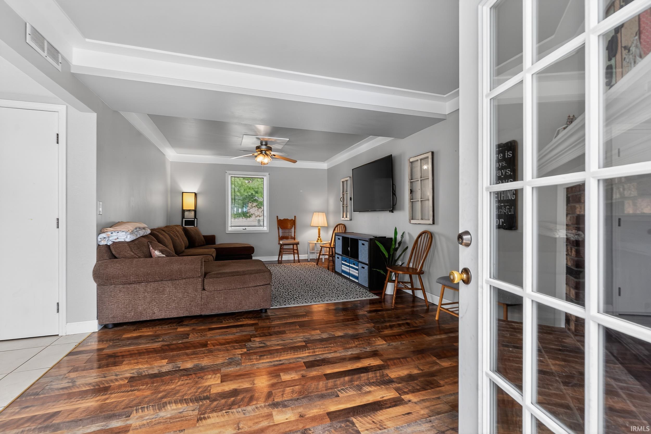 Living room with ornamental molding, ceiling fan, and wood finished floors