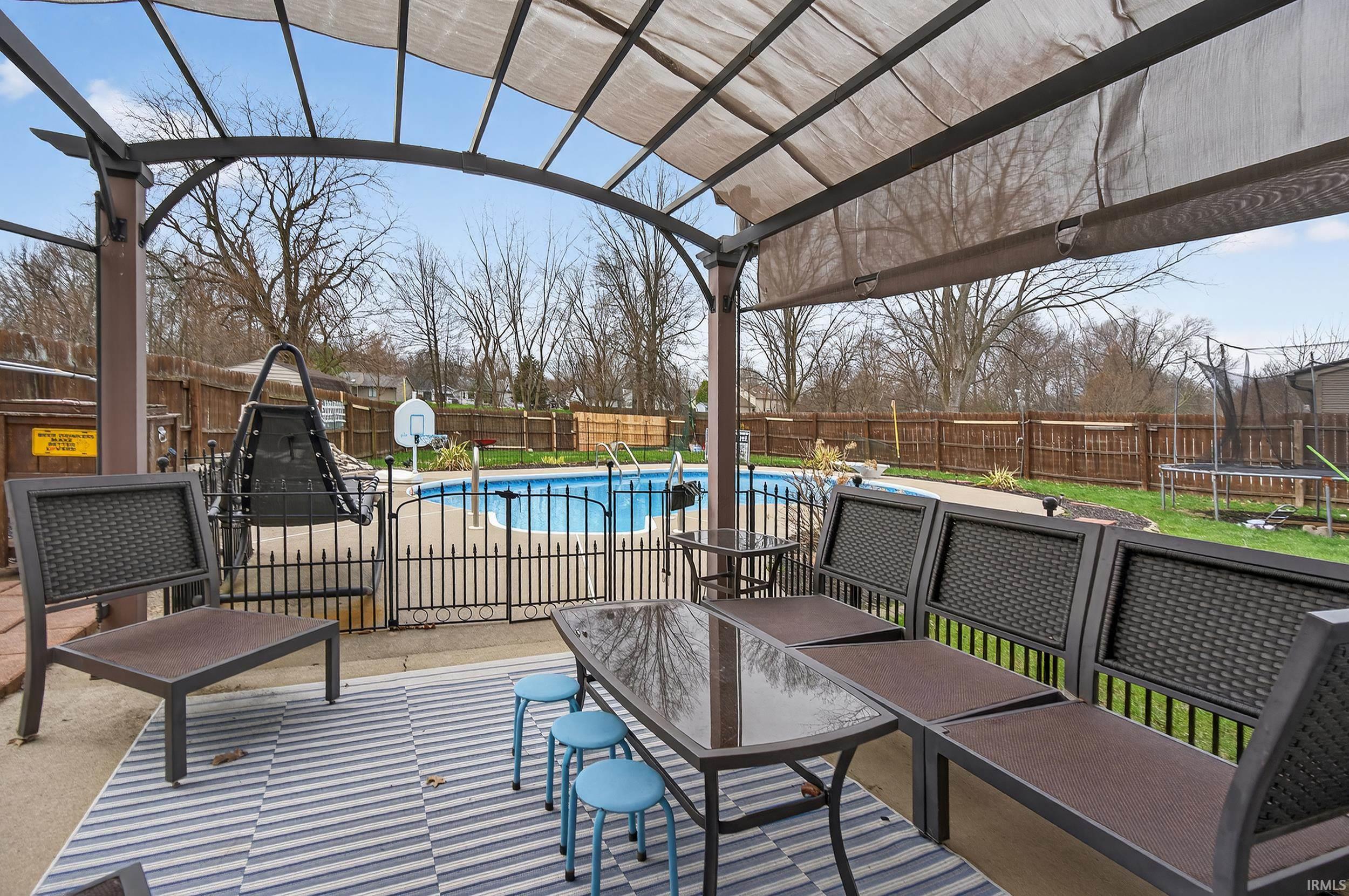 Fenced backyard featuring a trampoline, a patio, and a pergola