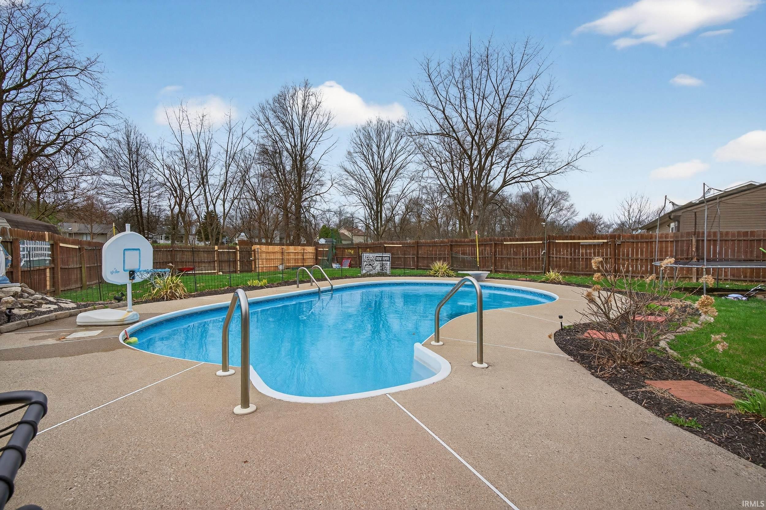 View of pool featuring a fenced backyard, patio surround, and a trampoline