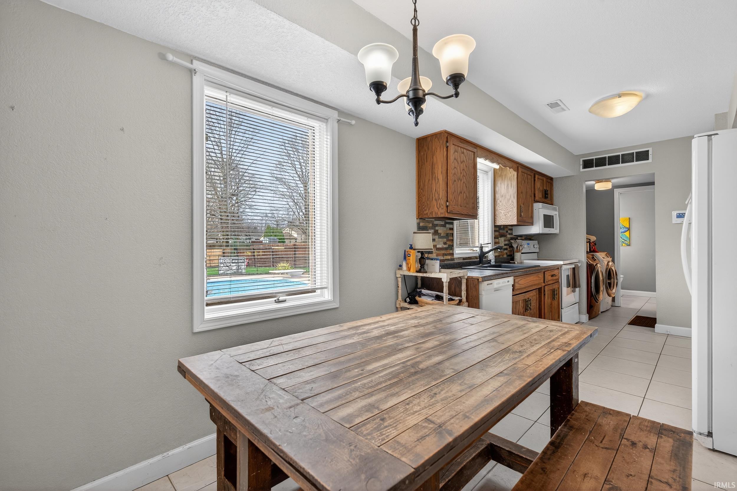 Dining room with washing machine and clothes dryer, suspended lighting, healthy amount of natural light, and light tile patterned flooring