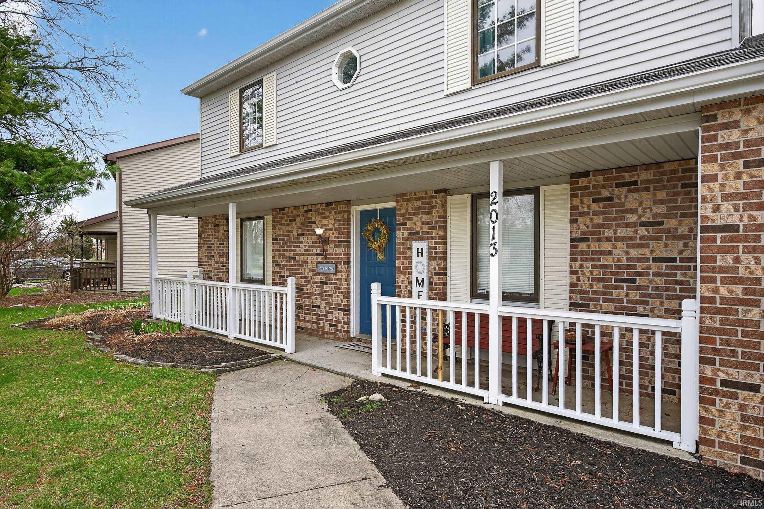 Property entrance featuring a porch and brick siding