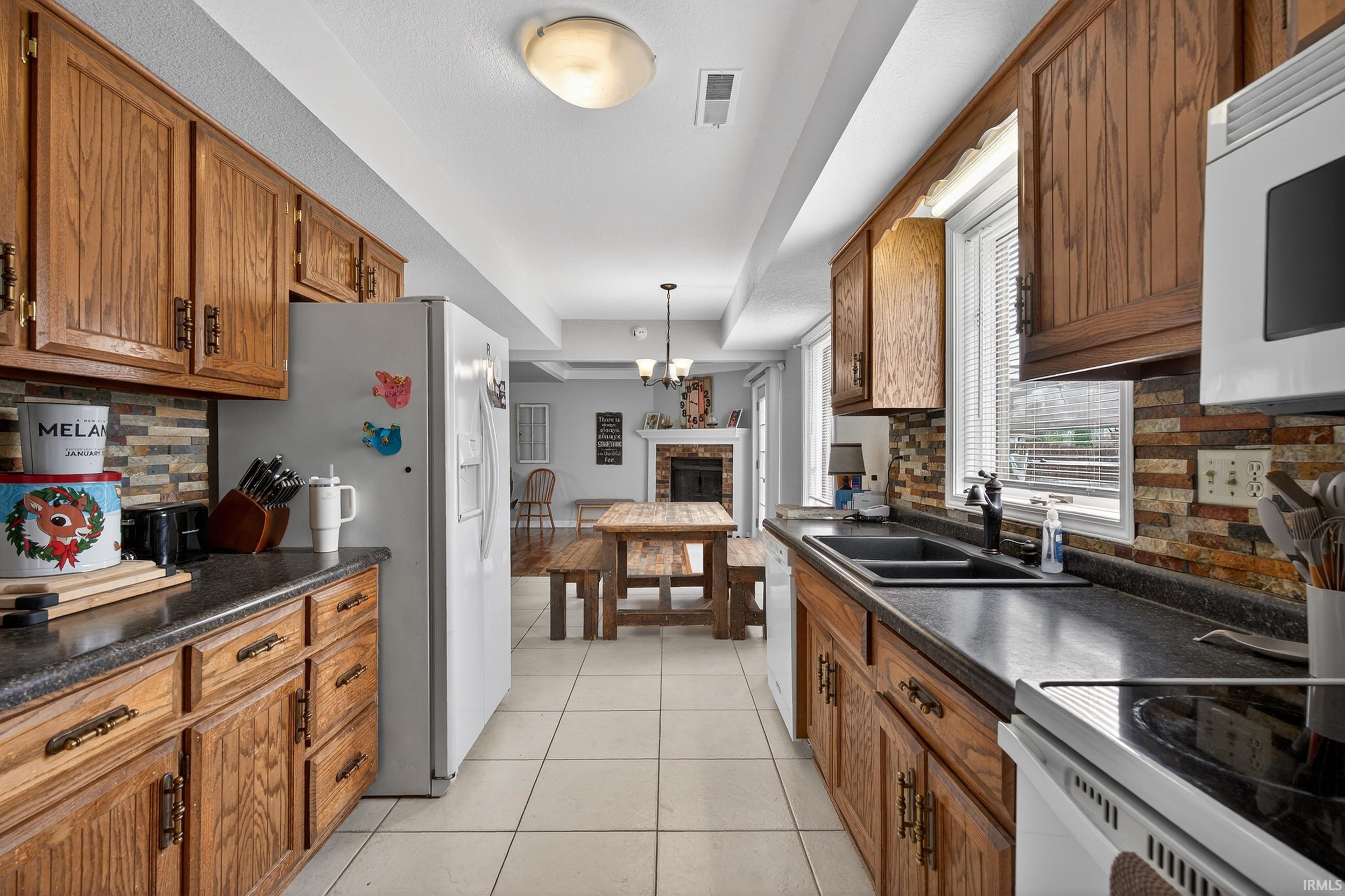 Kitchen with tasteful backsplash, dark countertops, and wood finish cabinetry
