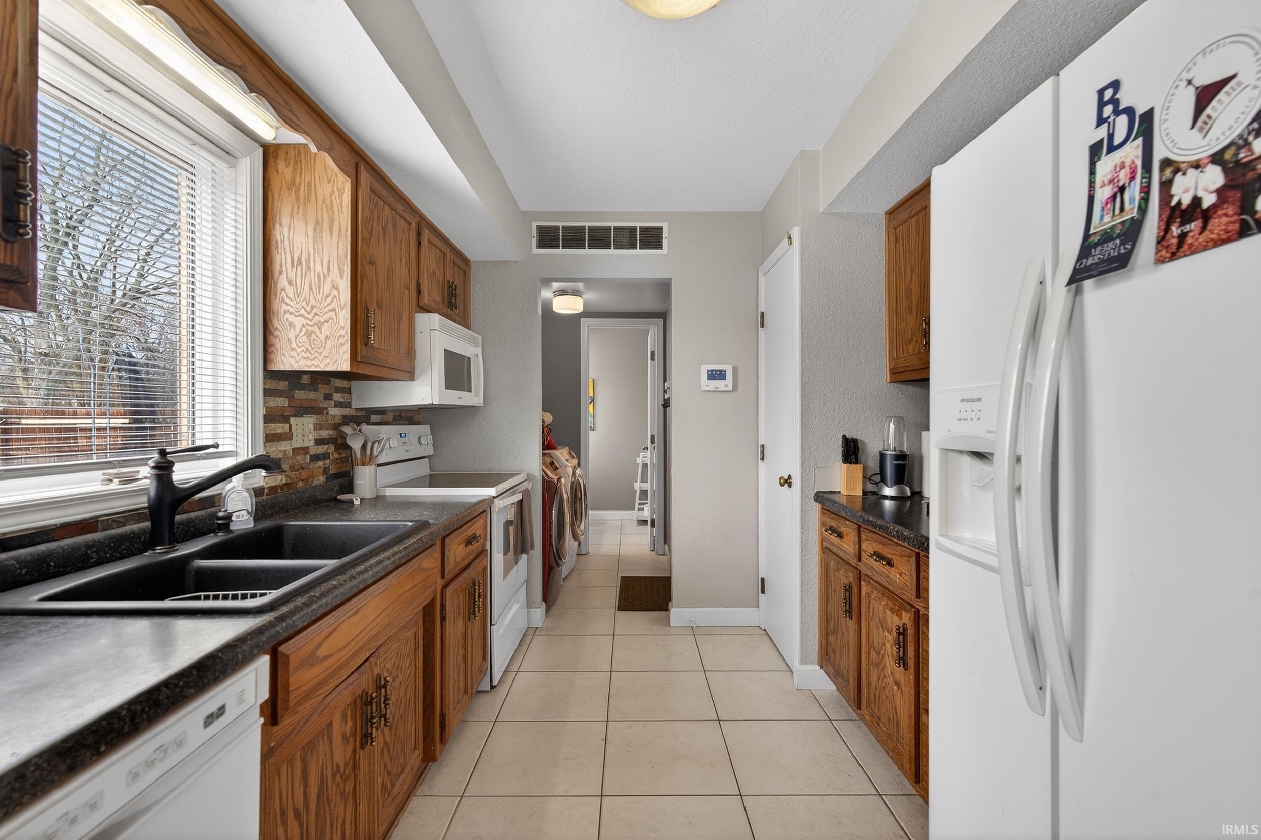 Kitchen featuring white appliances, dark countertops, and wood finish cabinets