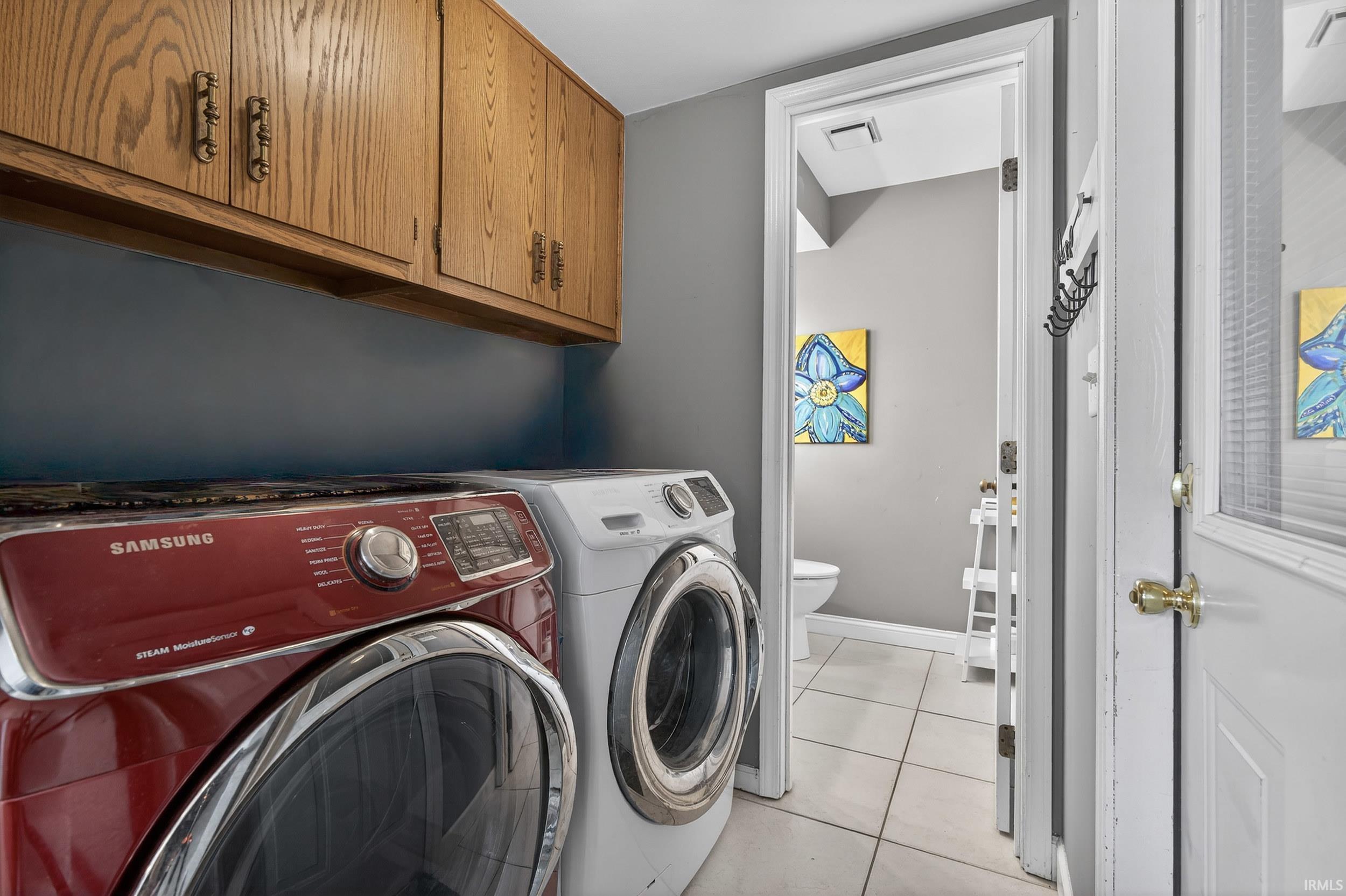 Laundry room with cabinet space, light tile patterned floors, and washer and clothes dryer