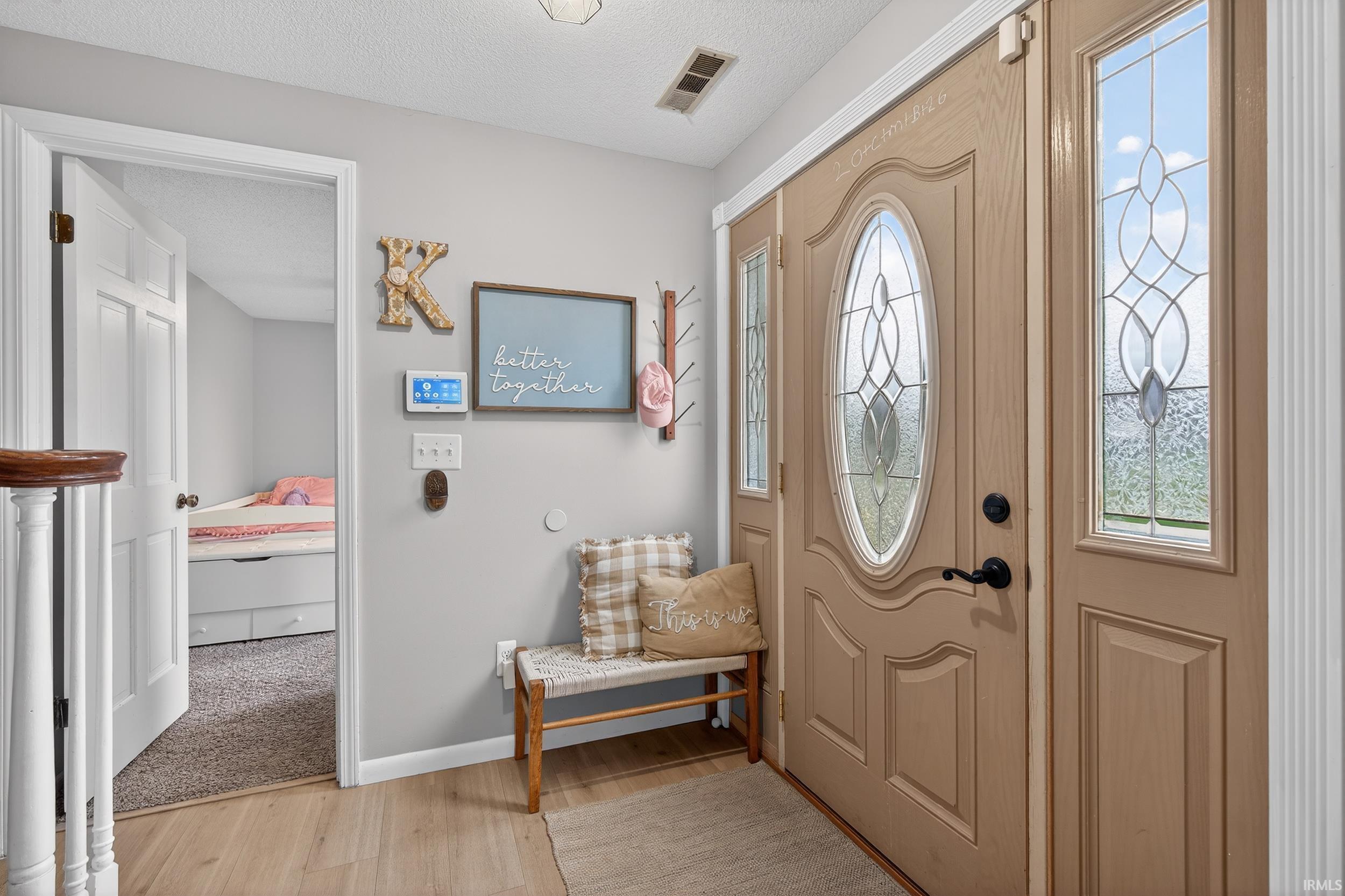 Foyer entrance featuring a textured ceiling and light wood-style floors
