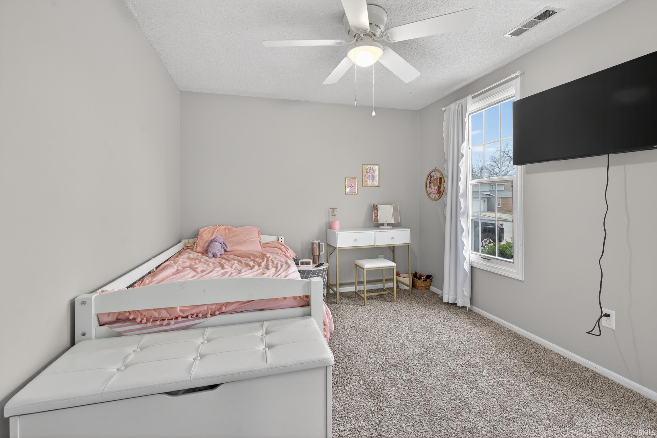 Bedroom with a ceiling fan, light colored carpet, and a textured ceiling