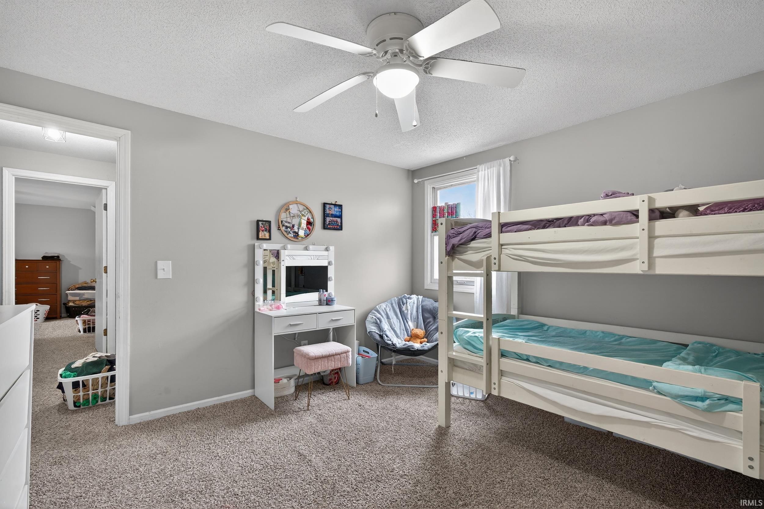 Bedroom with light colored carpet, a textured ceiling, and a ceiling fan