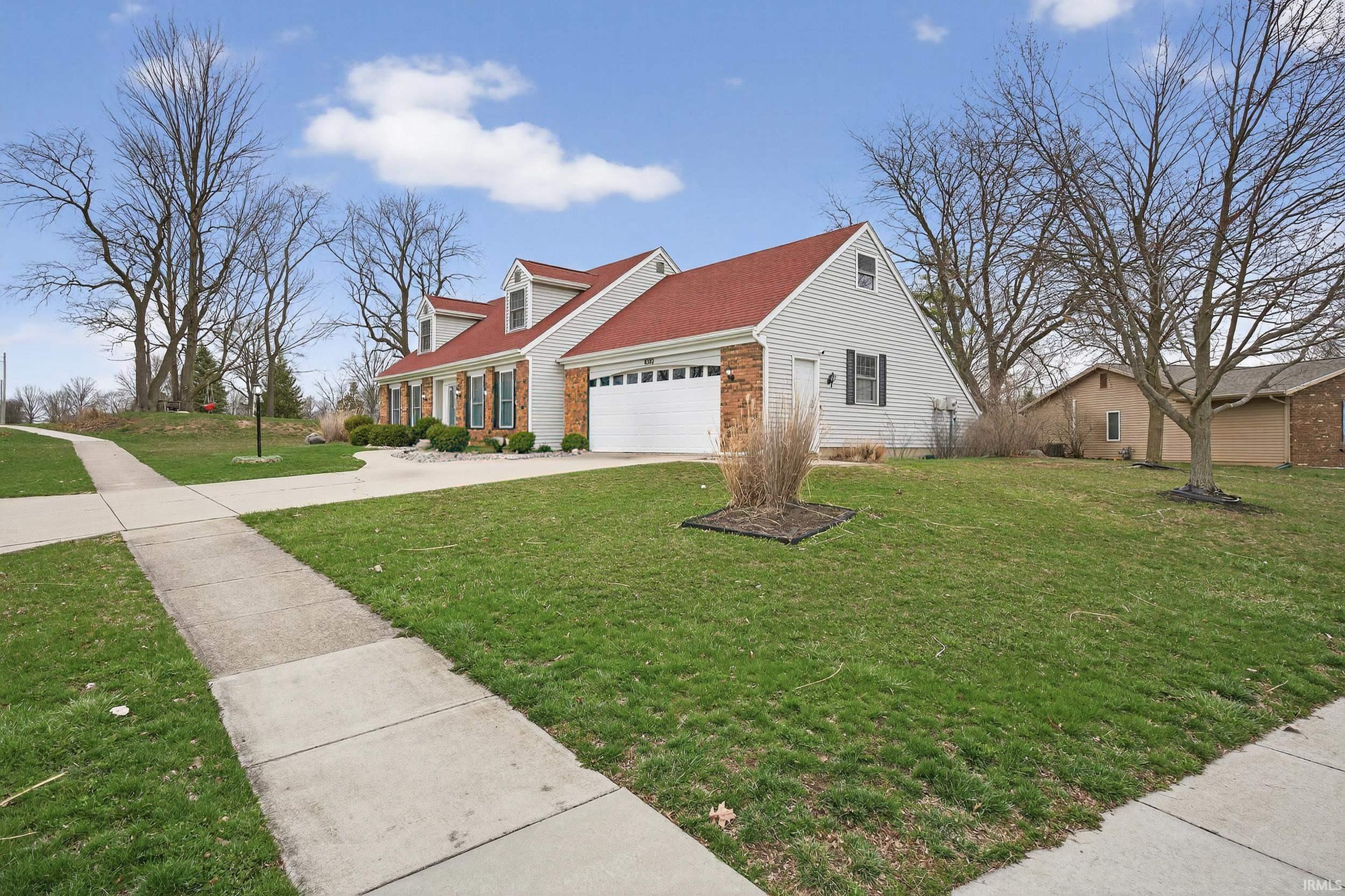 View of front of property featuring driveway, a garage, a front lawn, and brick siding