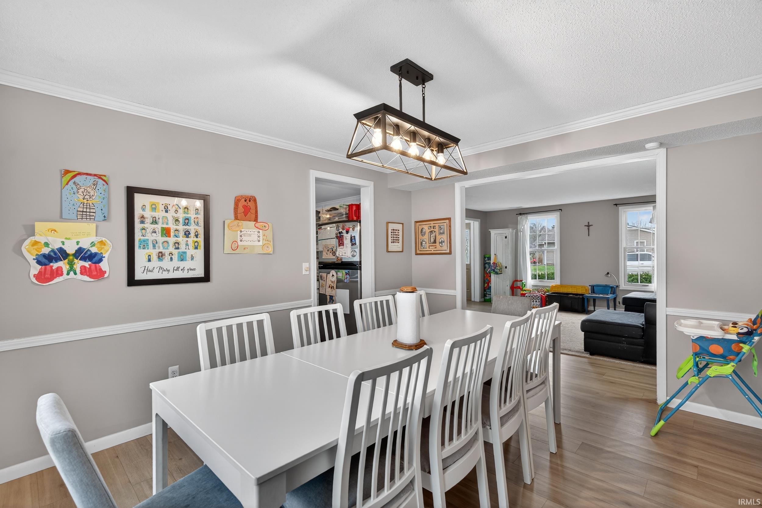 Dining space featuring light wood-style flooring, crown molding, and a chandelier