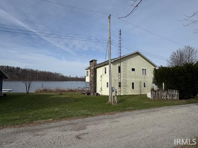 View of home's exterior featuring a chimney and a lawn
