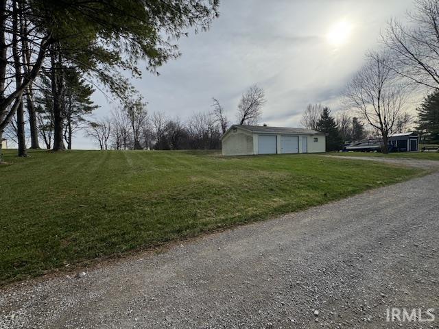 View of green lawn featuring a garage and an outdoor structure