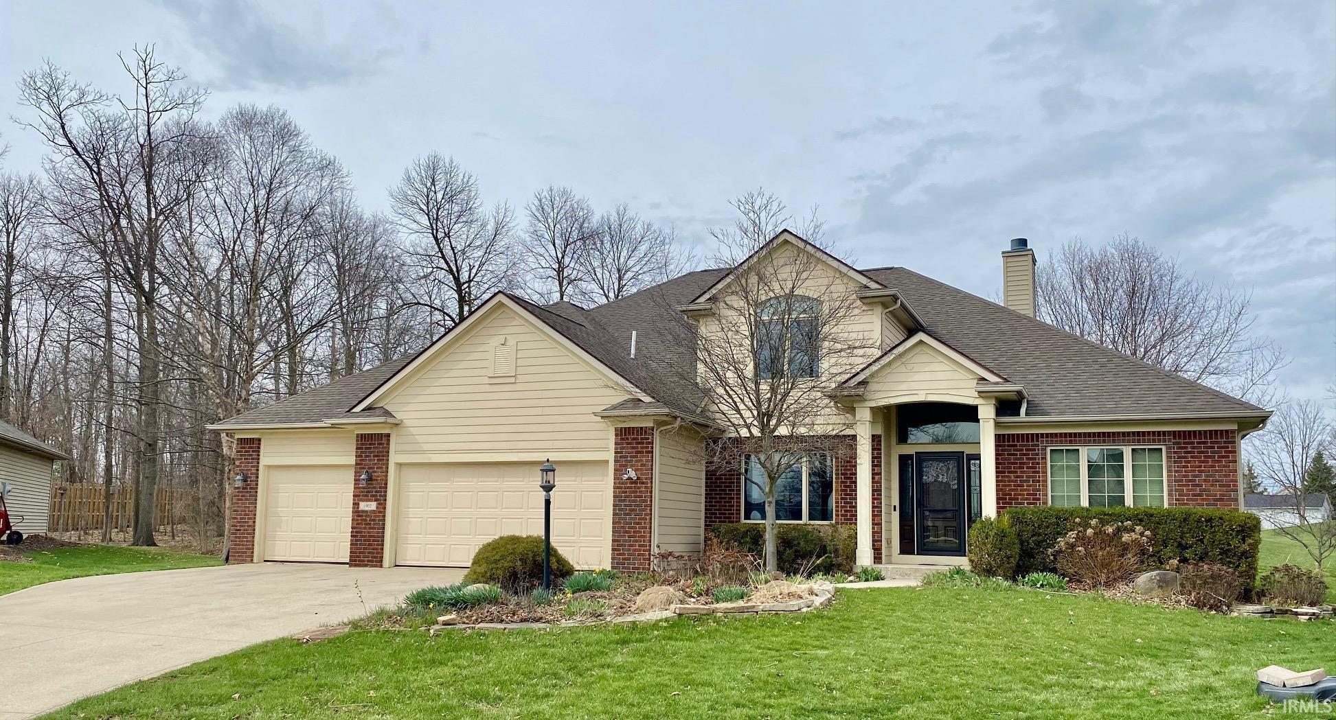 View of front facade featuring brick siding, a front lawn, and a shingled roof
