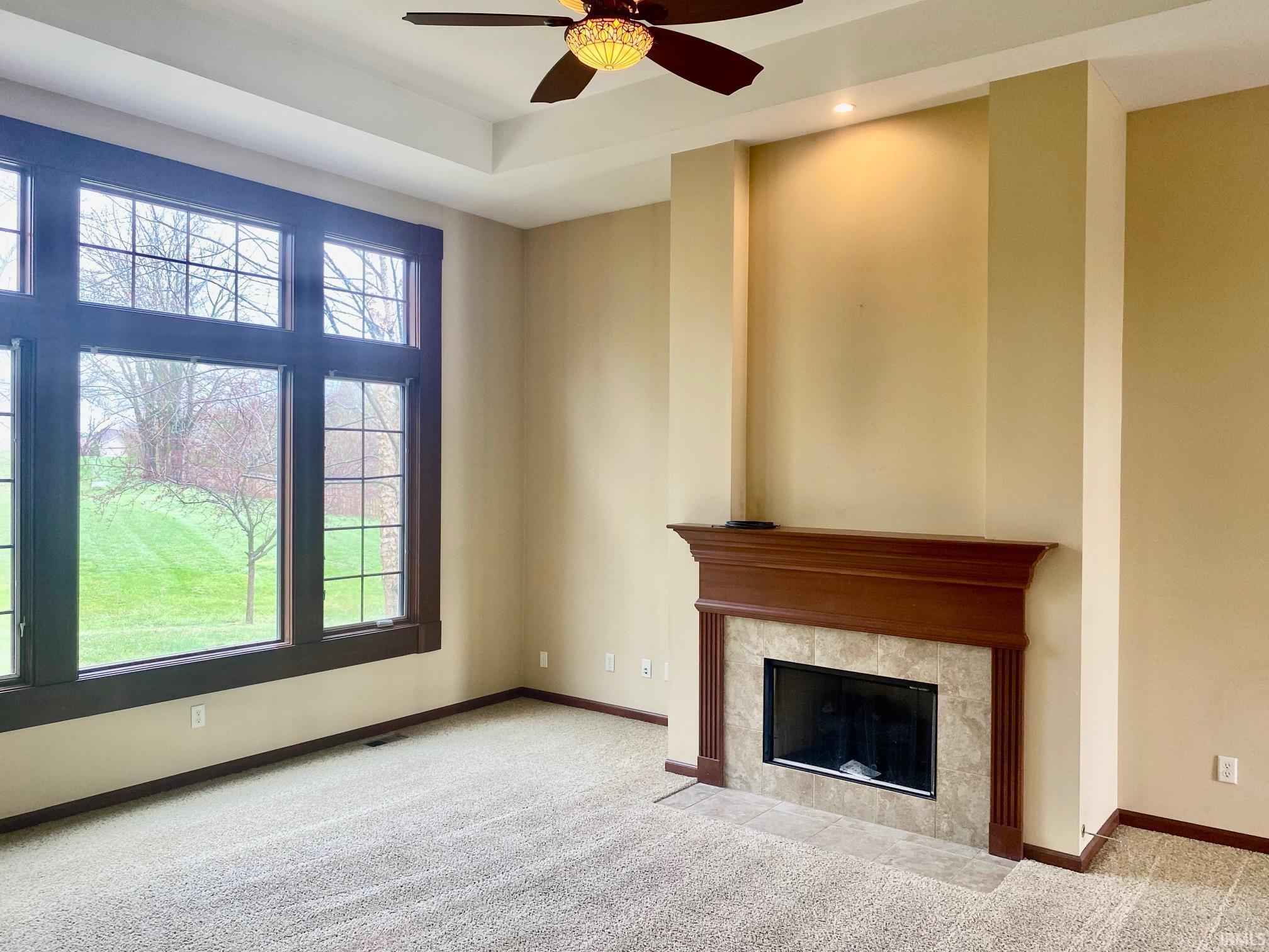 Unfurnished living room with light carpet, ceiling fan, and a fireplace