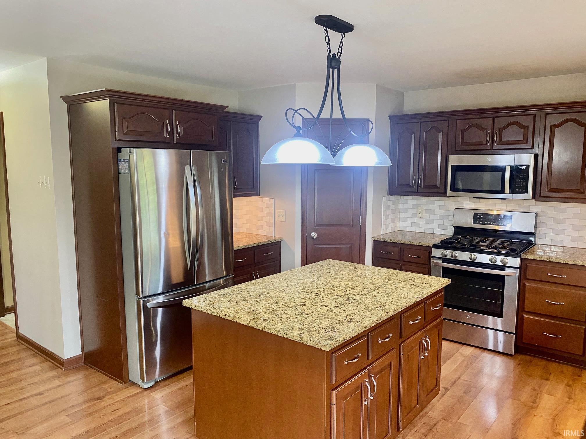 Kitchen with stainless steel appliances, backsplash, pendant lighting, and a kitchen island