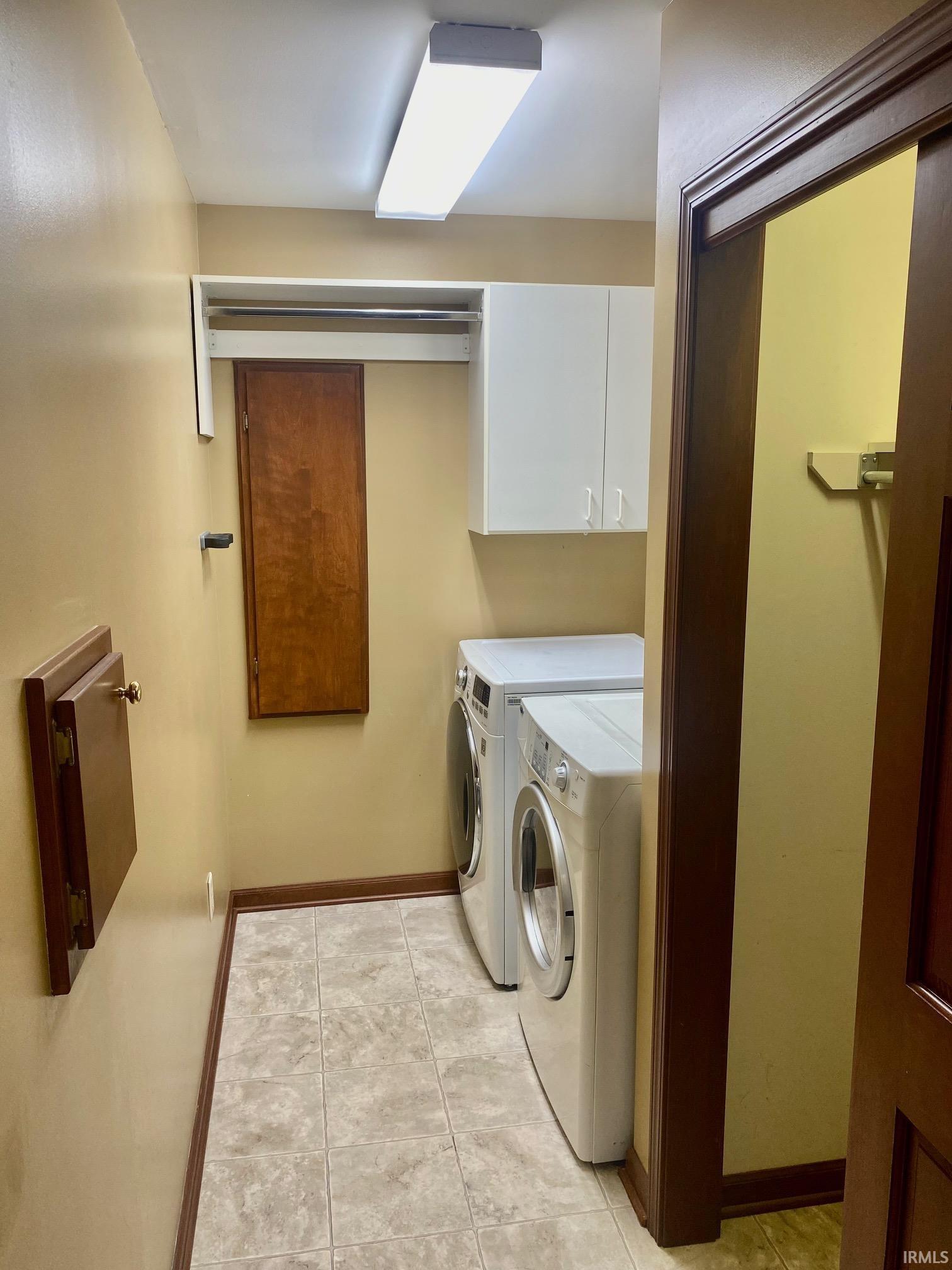 Laundry room with cabinet space, independent washer and dryer, and light tile patterned flooring