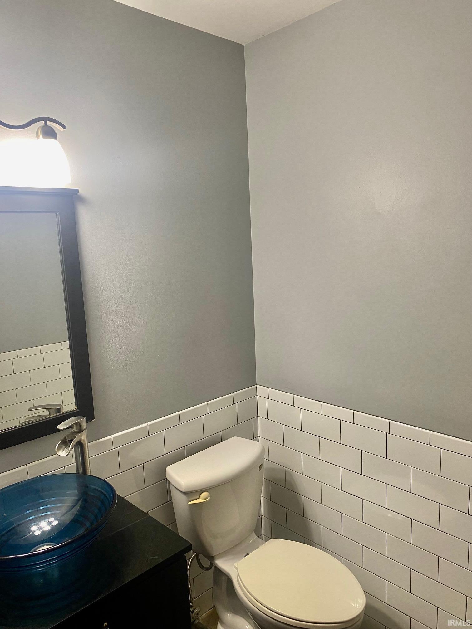 Bathroom with vanity, tile walls, and wainscoting