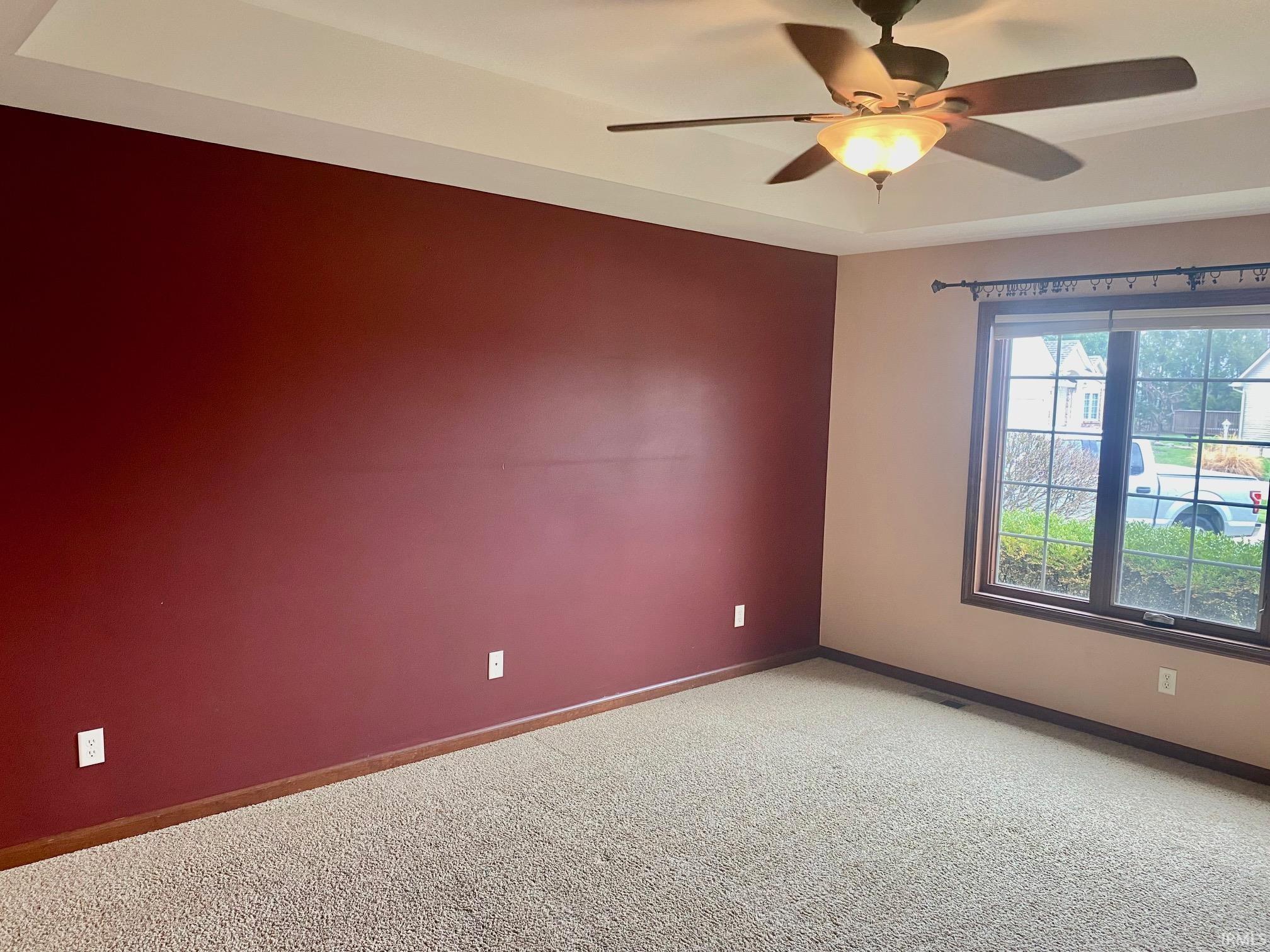 Carpeted spare room featuring a ceiling fan and baseboards