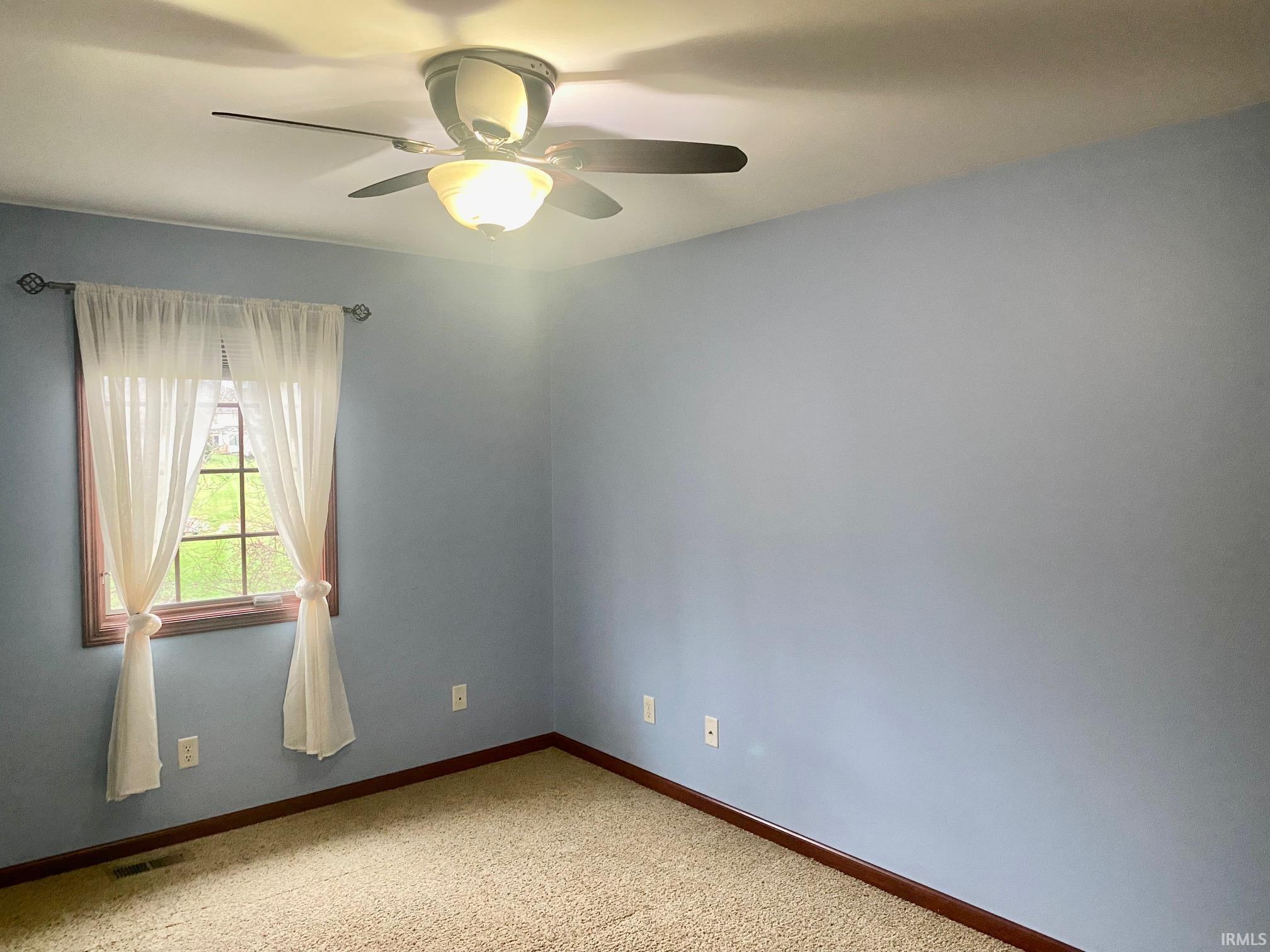 Empty room featuring ceiling fan and light carpet