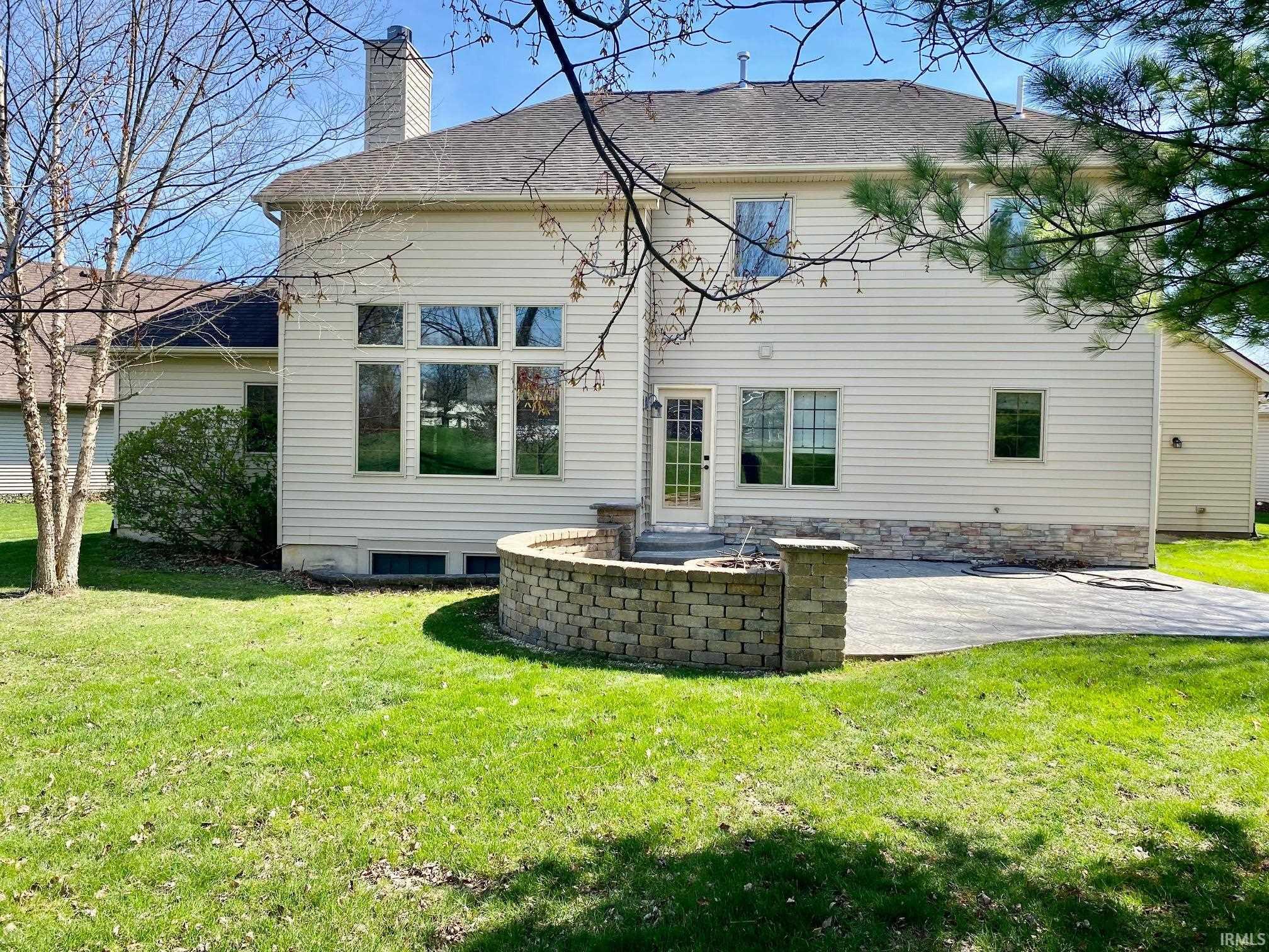Back of house featuring a chimney, a lawn, and a patio