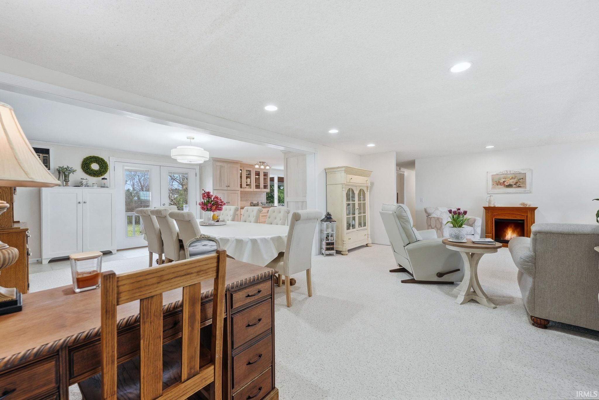 Dining space featuring light carpet, recessed lighting, and a warm lit fireplace