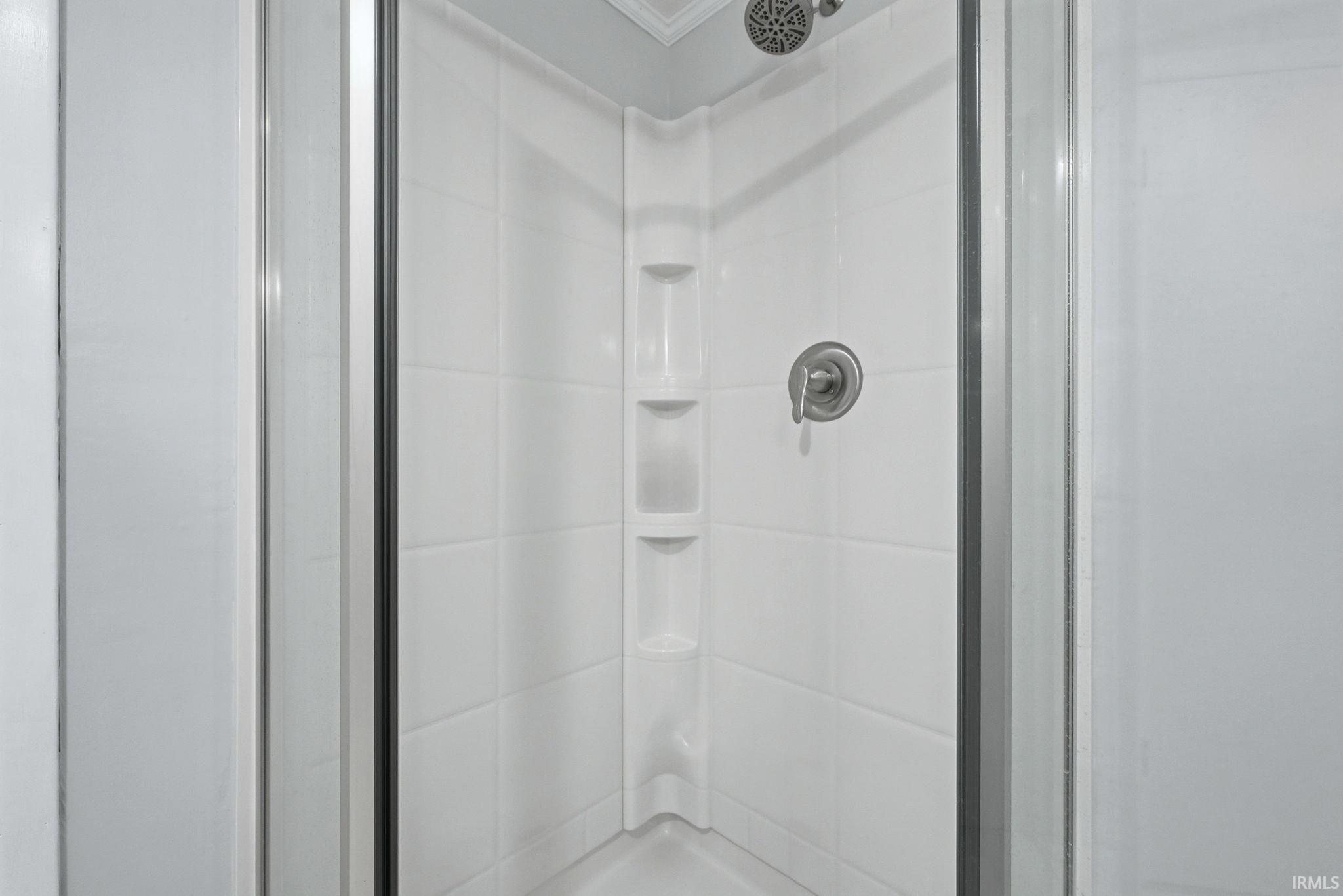Full bathroom featuring a stall shower and crown molding