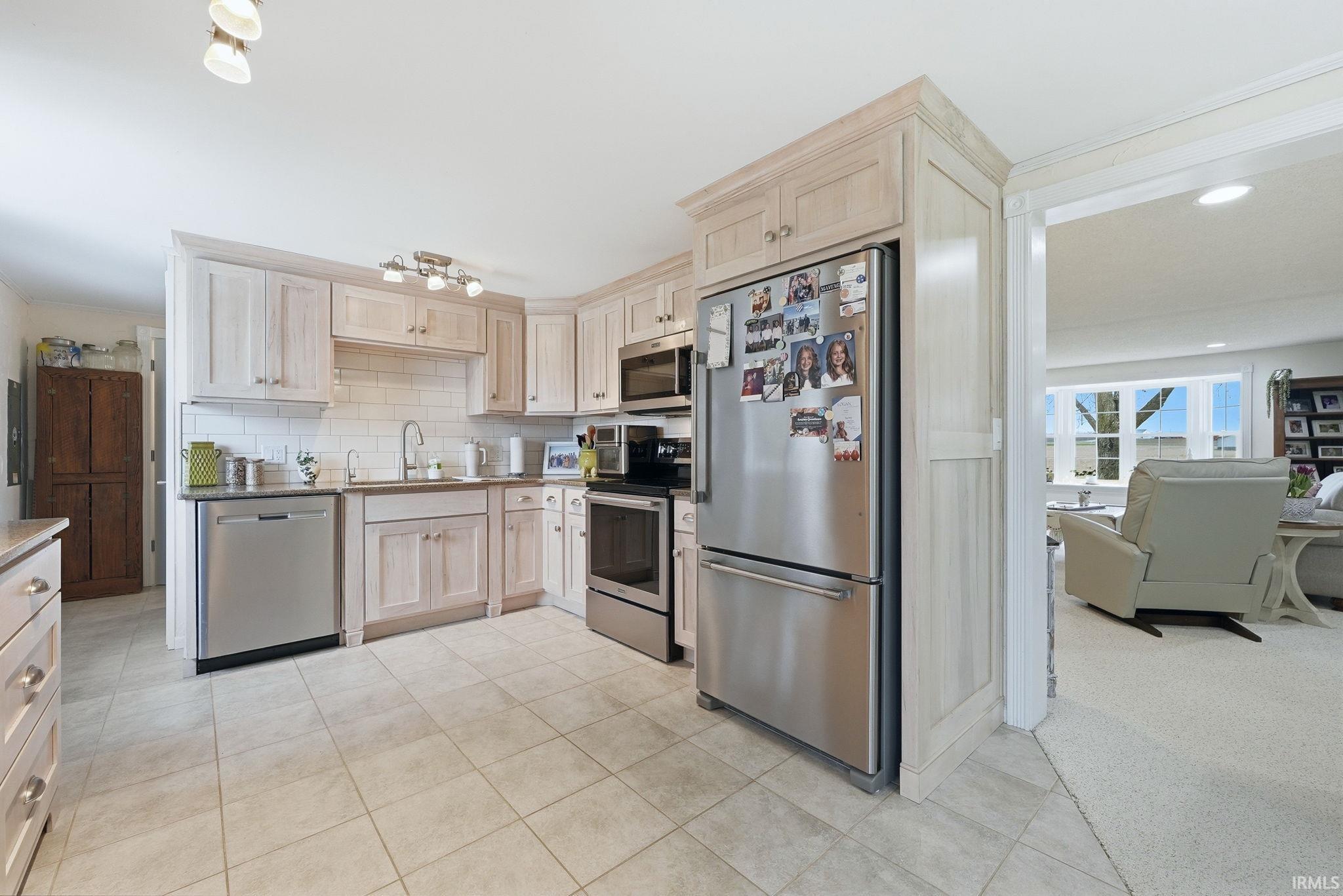 Kitchen with stainless steel appliances, light wood finish cabinets, ornamental molding, recessed lighting, and backsplash