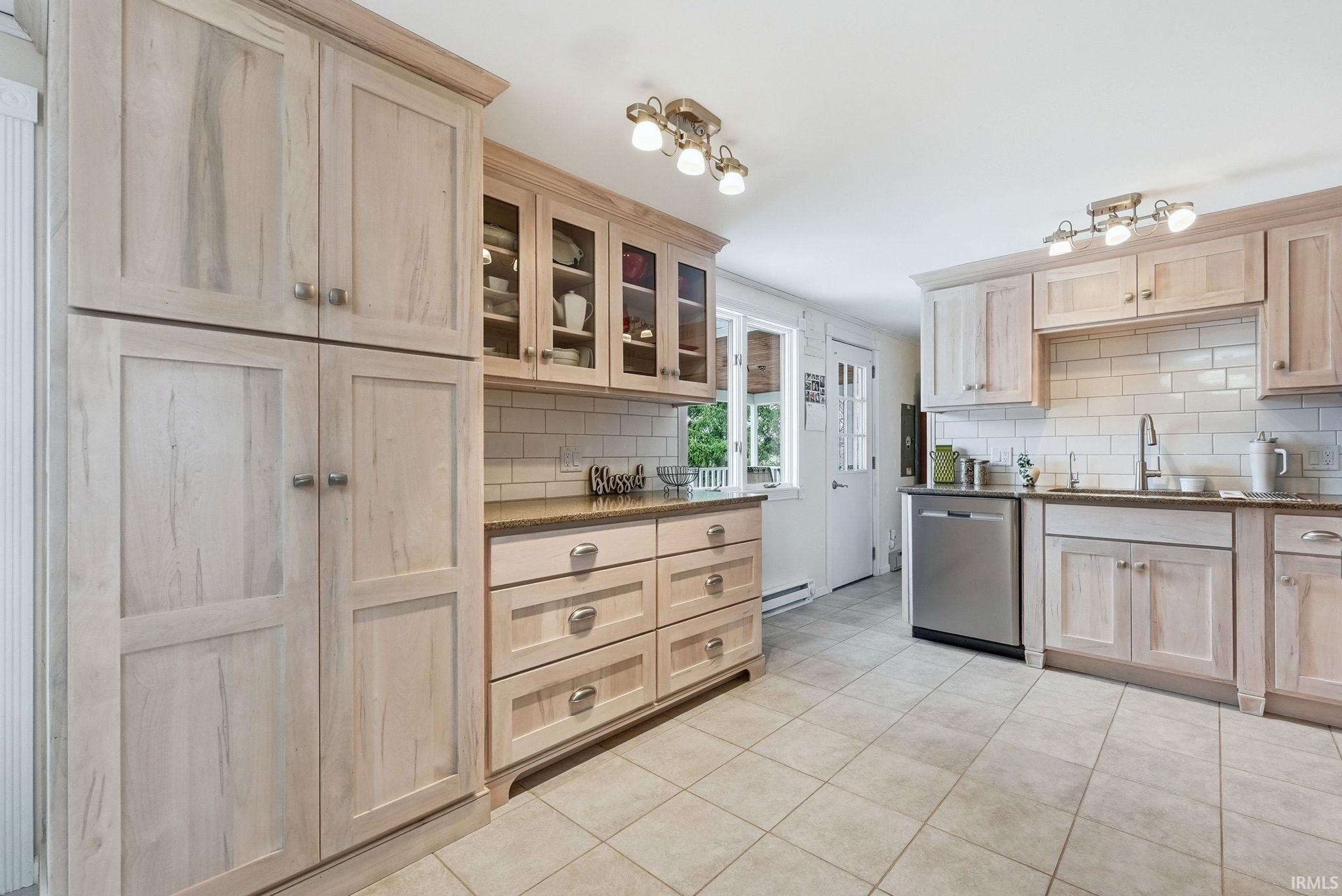 Kitchen with light wood finish cabinetry, dishwasher, and tasteful backsplash