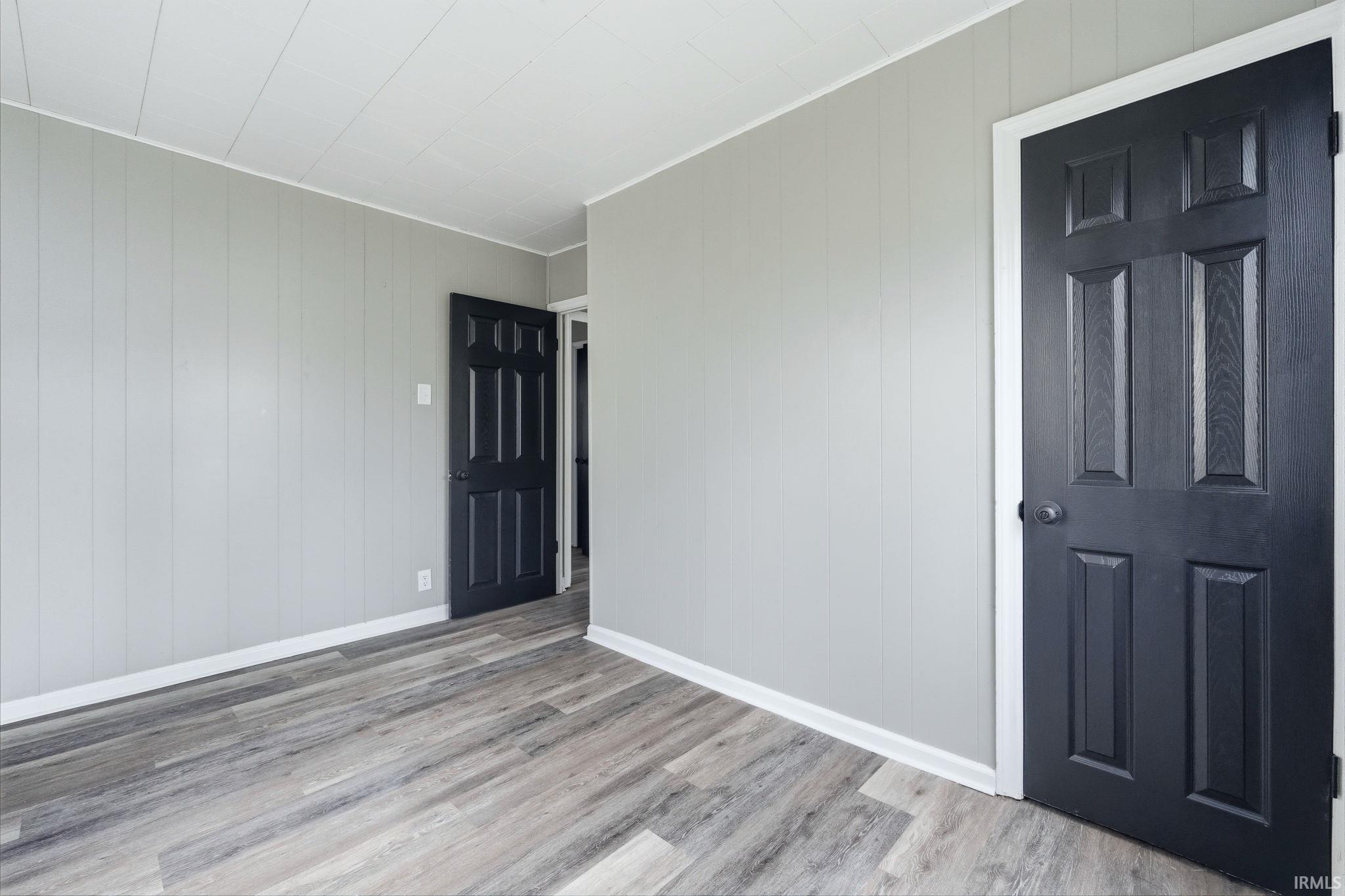 Spare room with light wood-style floors, wood walls, and ornamental molding