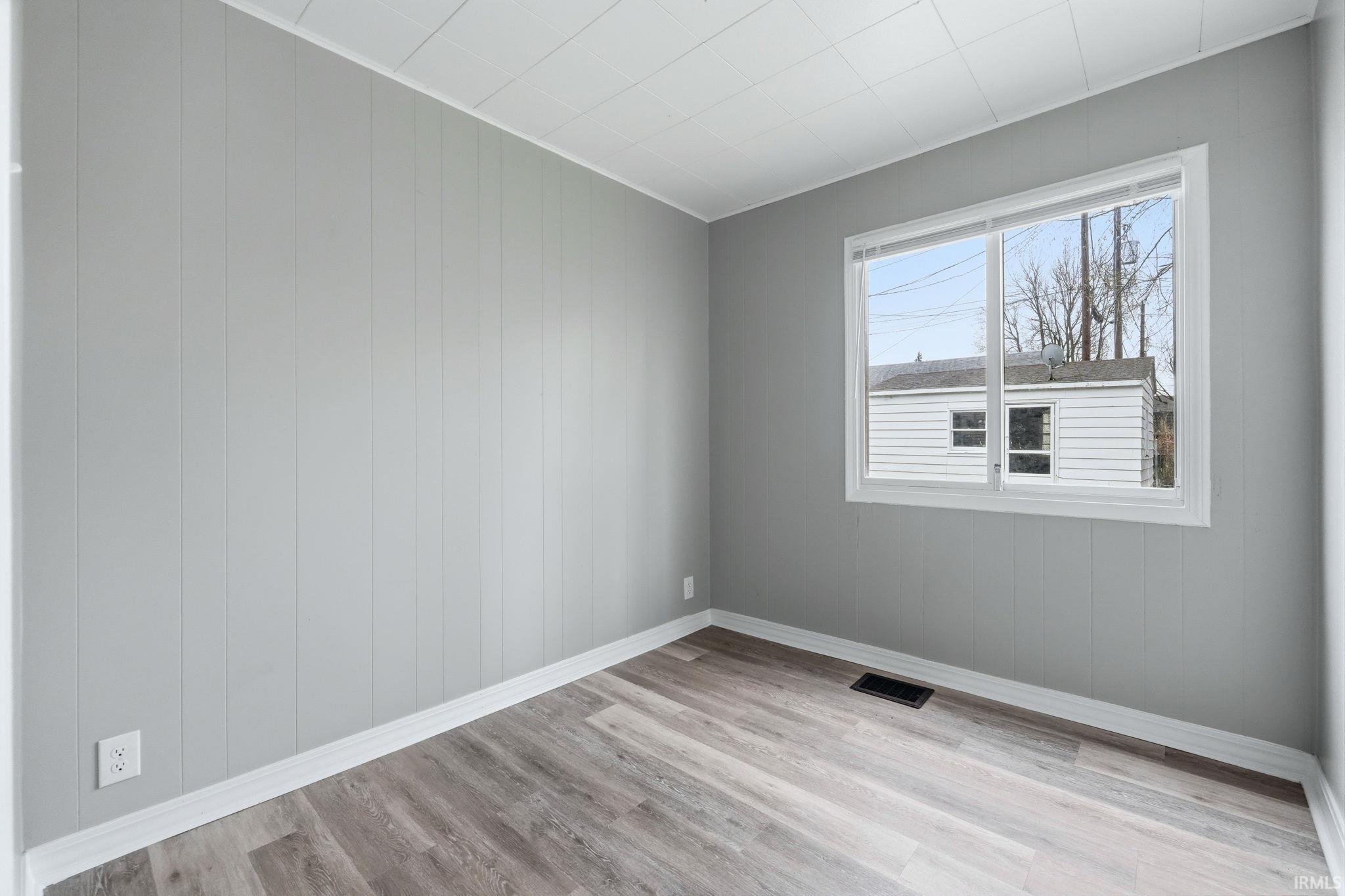 Spare room with light wood-type flooring and wooden walls