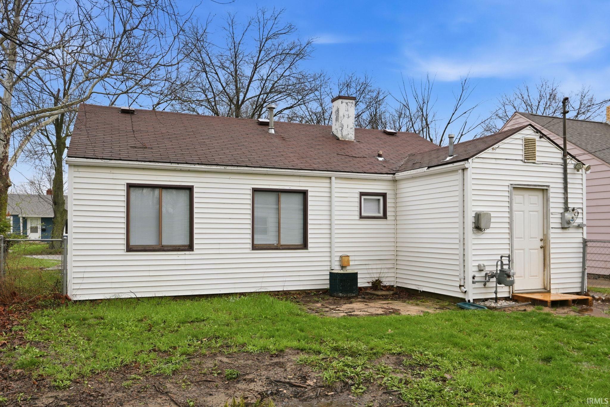 Back of property featuring a chimney and roof with shingles