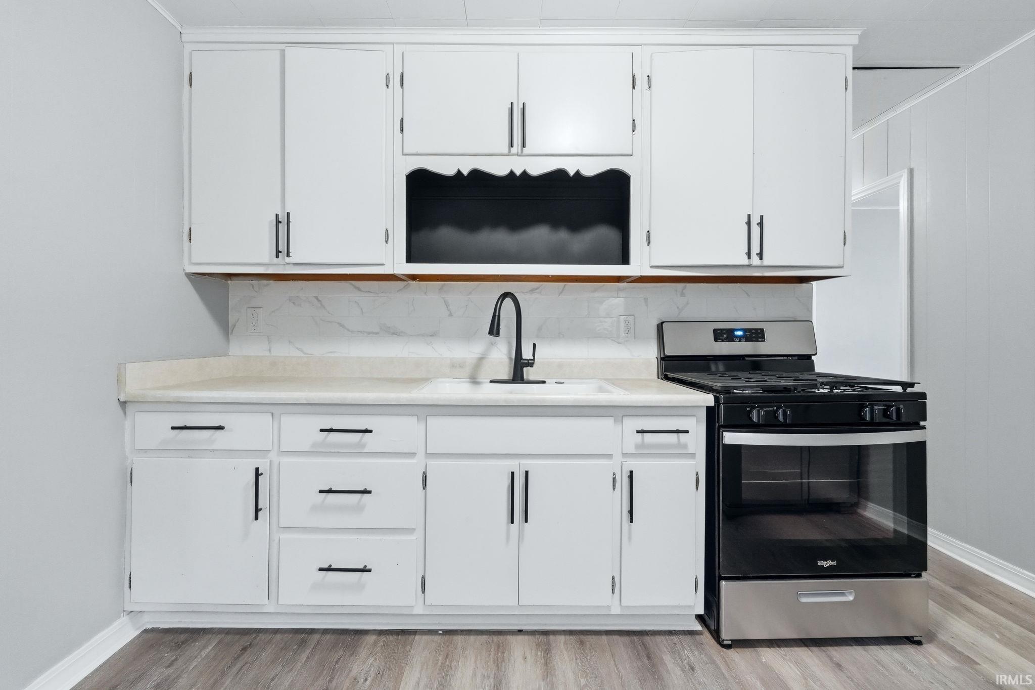 Kitchen with gas stove, light countertops, and white cabinets
