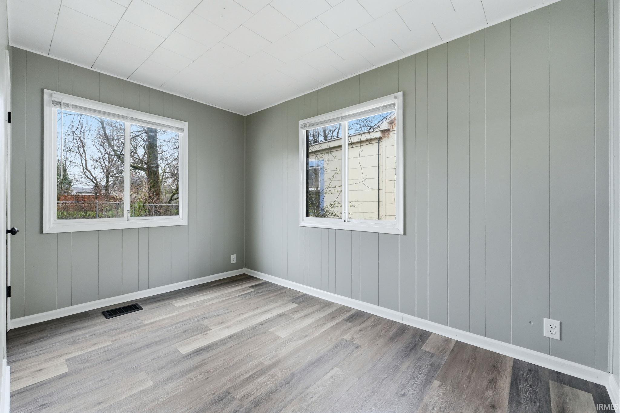 Spare room with light wood-style floors and wooden walls