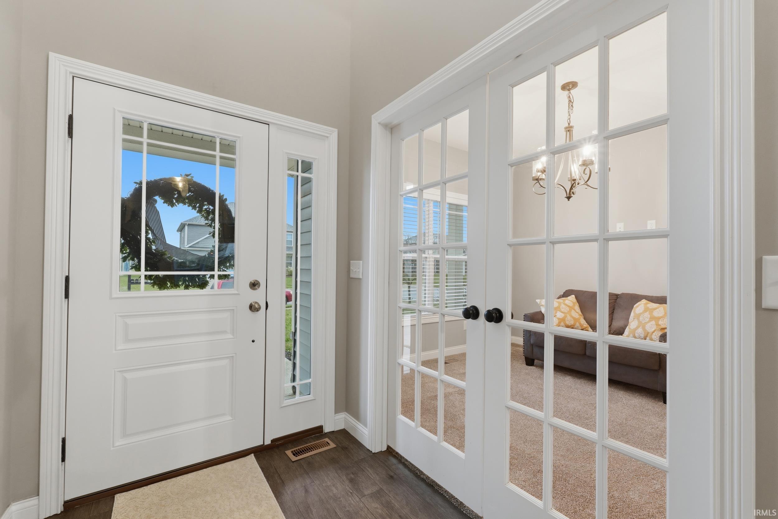 Foyer featuring dark wood-type flooring, french doors, and a chandelier