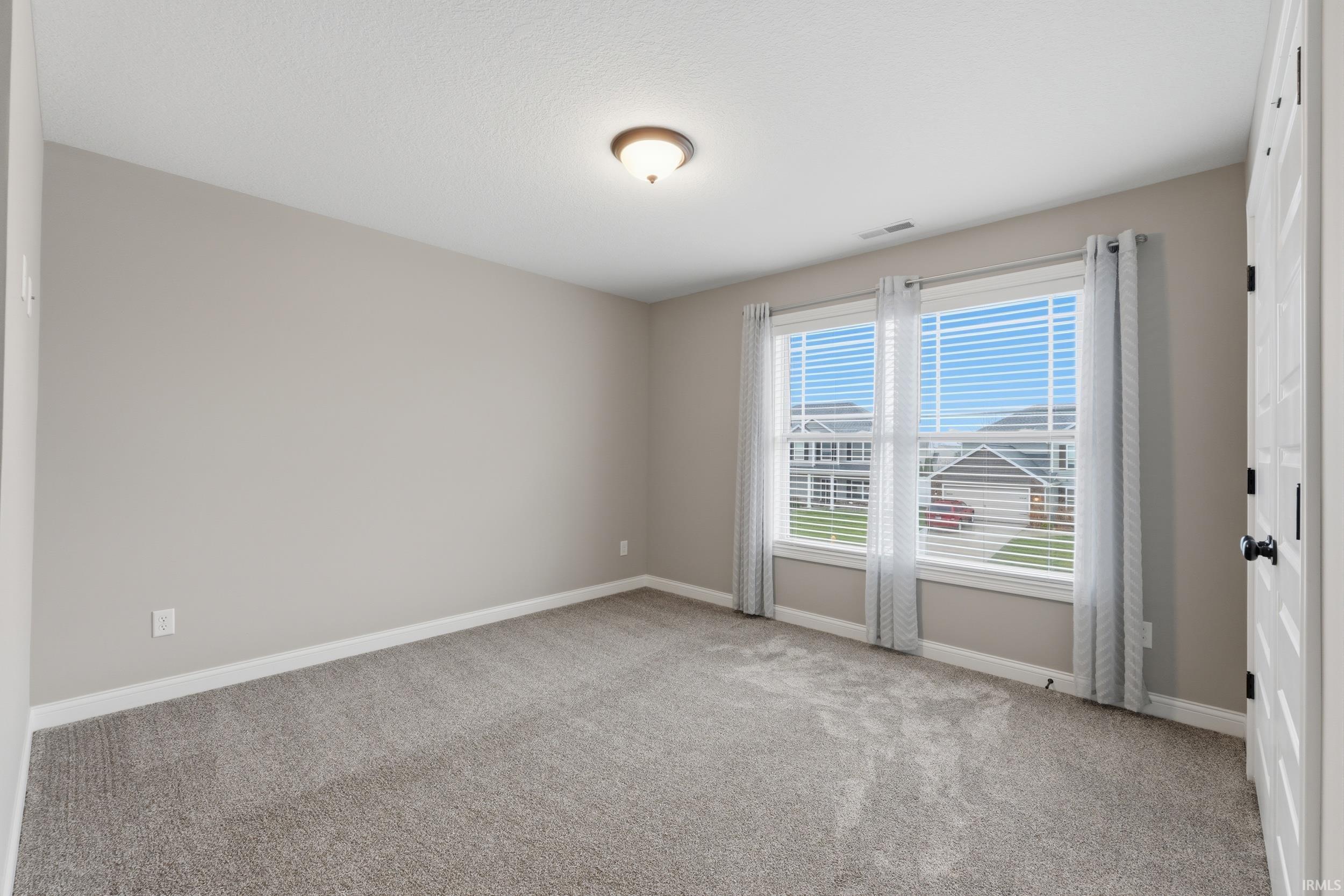 Empty room with light colored carpet and baseboards