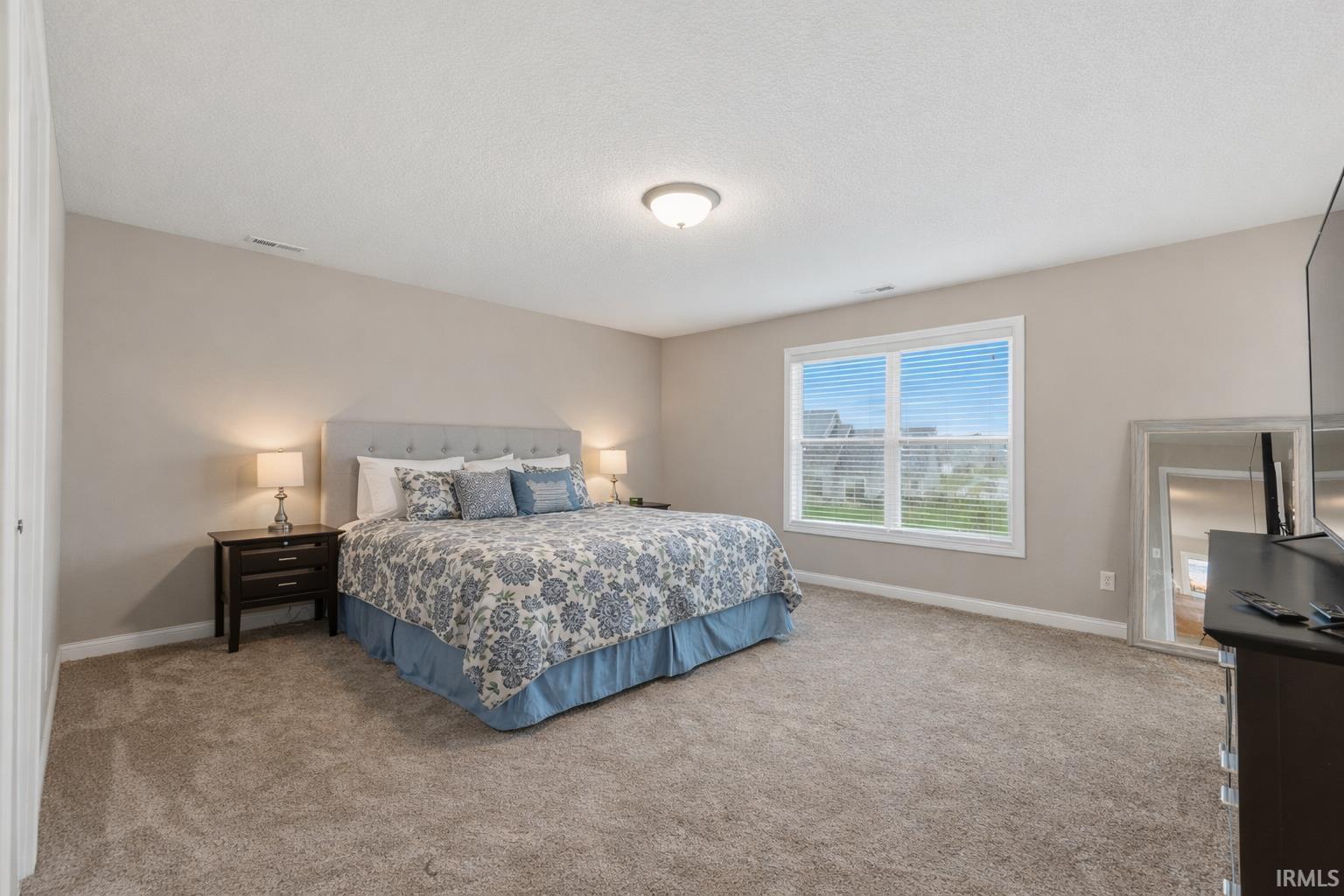 Bedroom featuring light carpet and a textured ceiling
